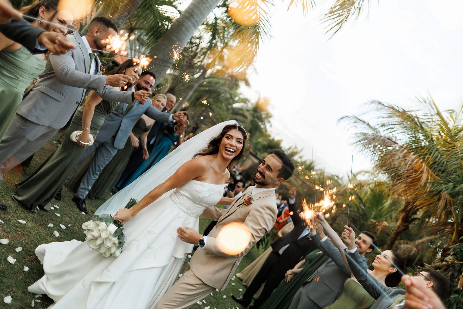 Joyful wedding celebration with guests gathered outdoors at sunset.