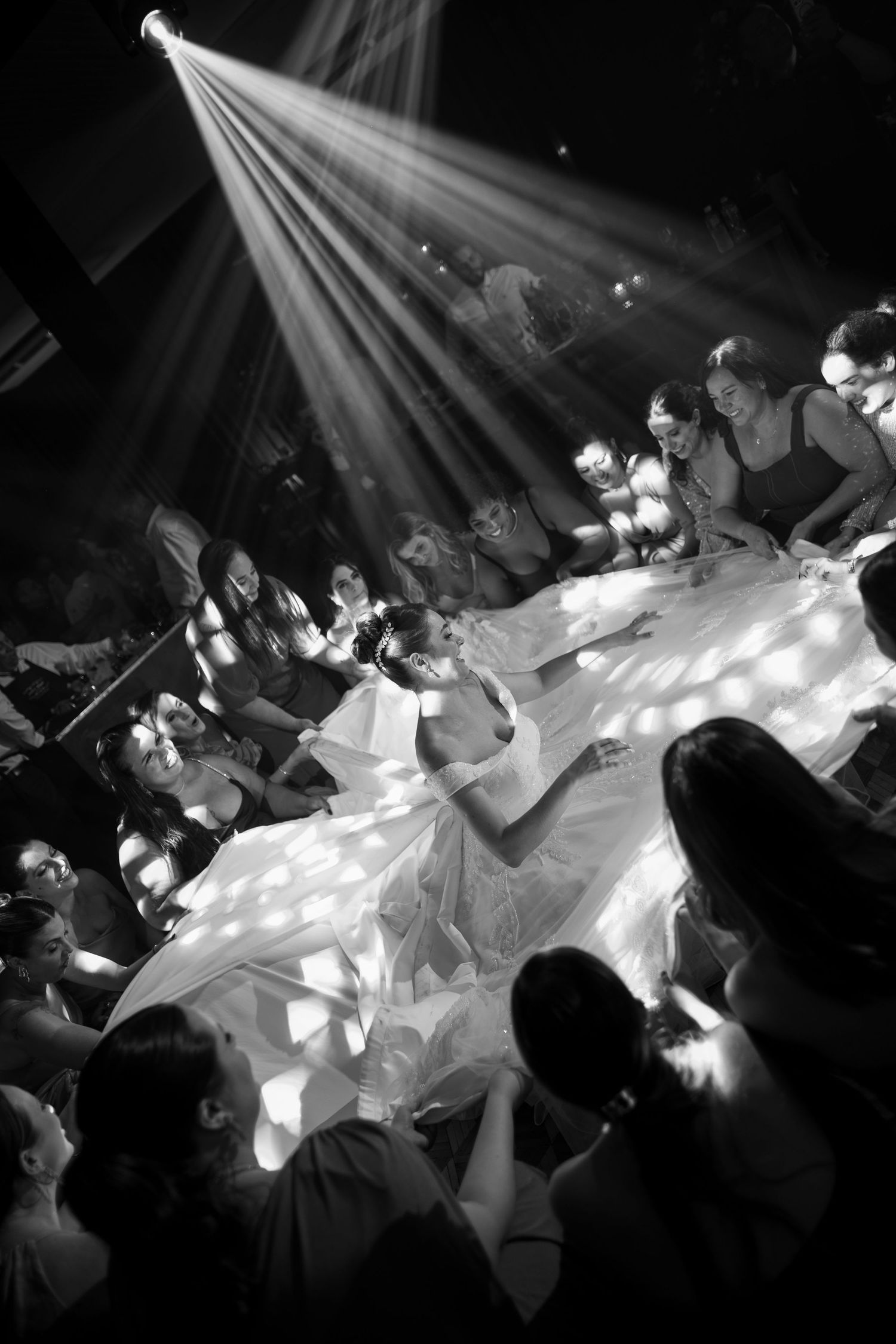Wedding reception dance floor scene with dramatic spotlight effects in black and white.