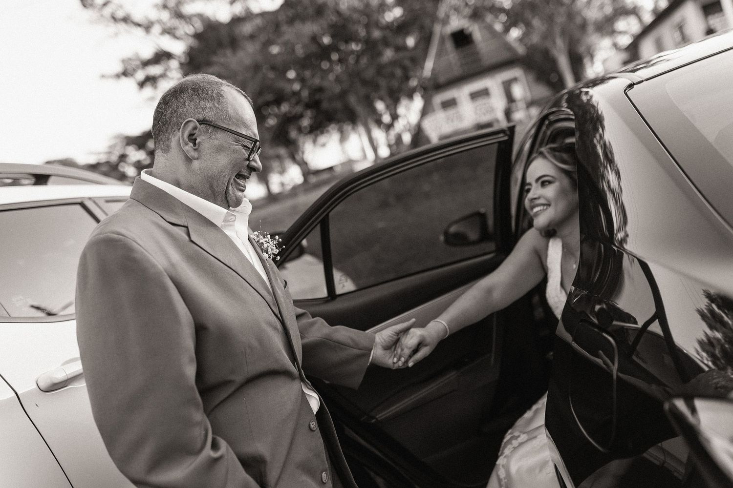 A couple shares an intimate moment while entering a black car after their wedding ceremony.