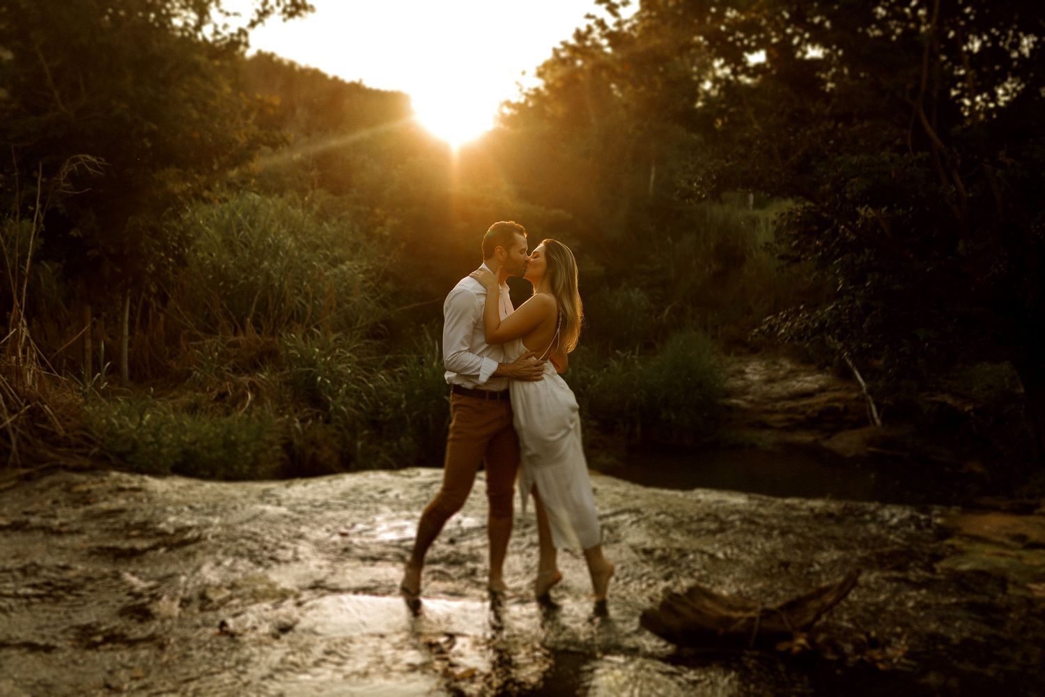 Silhouettes of a couple embracing during sunset in a natural outdoor setting.