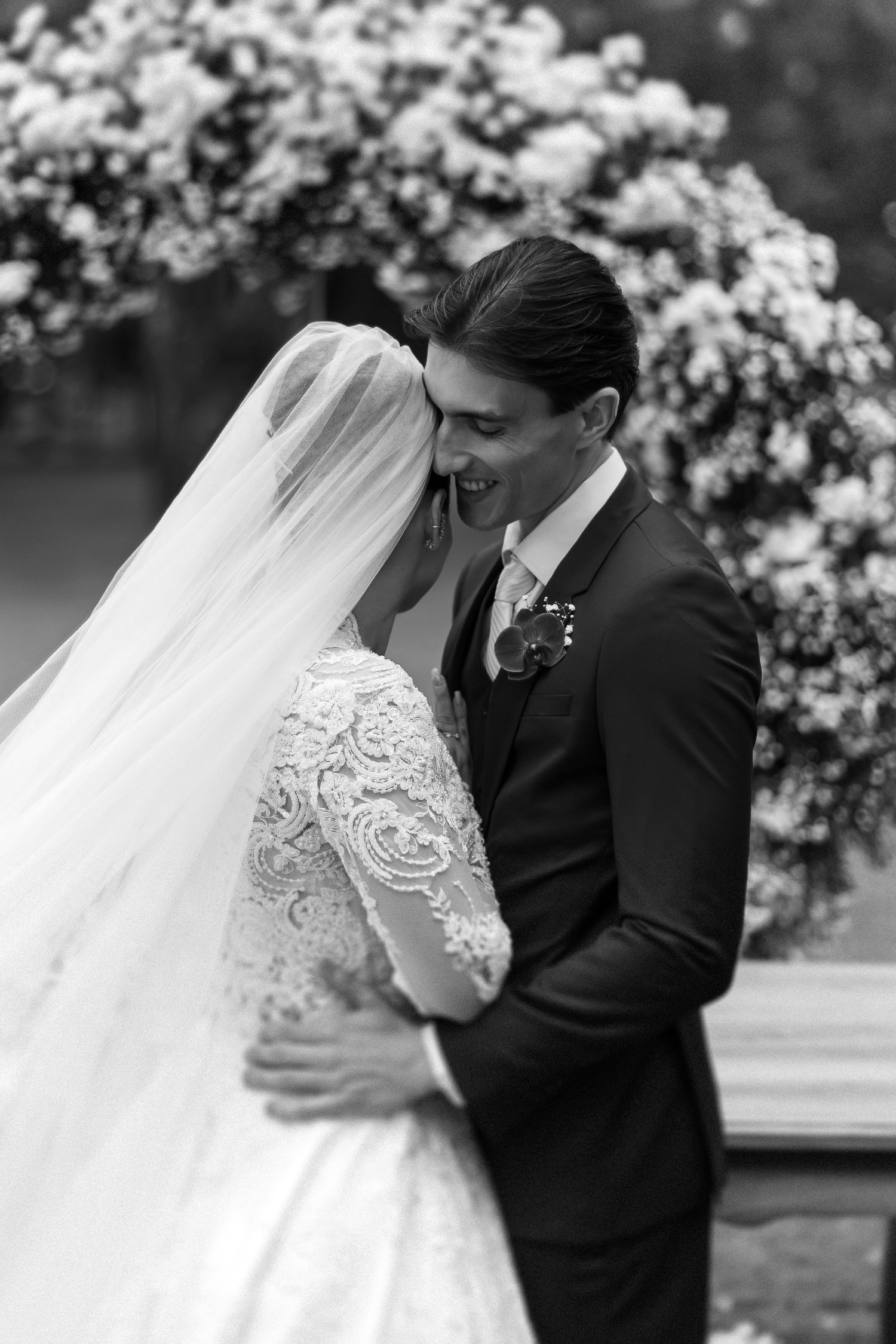 Black and white wedding portrait with blooming cherry blossoms in the background.
