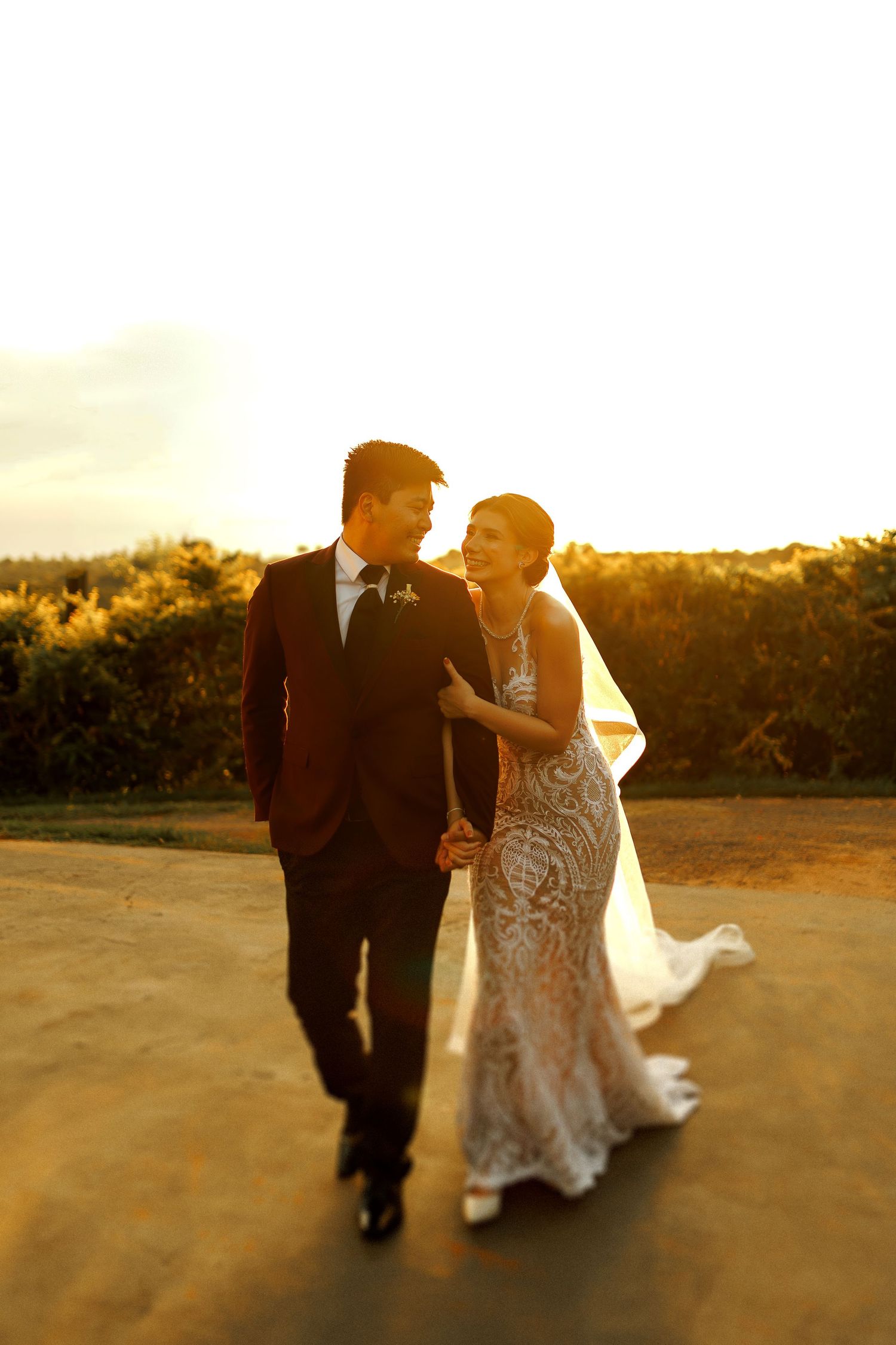 Wedding couple walking together during golden hour sunset on a beach path.