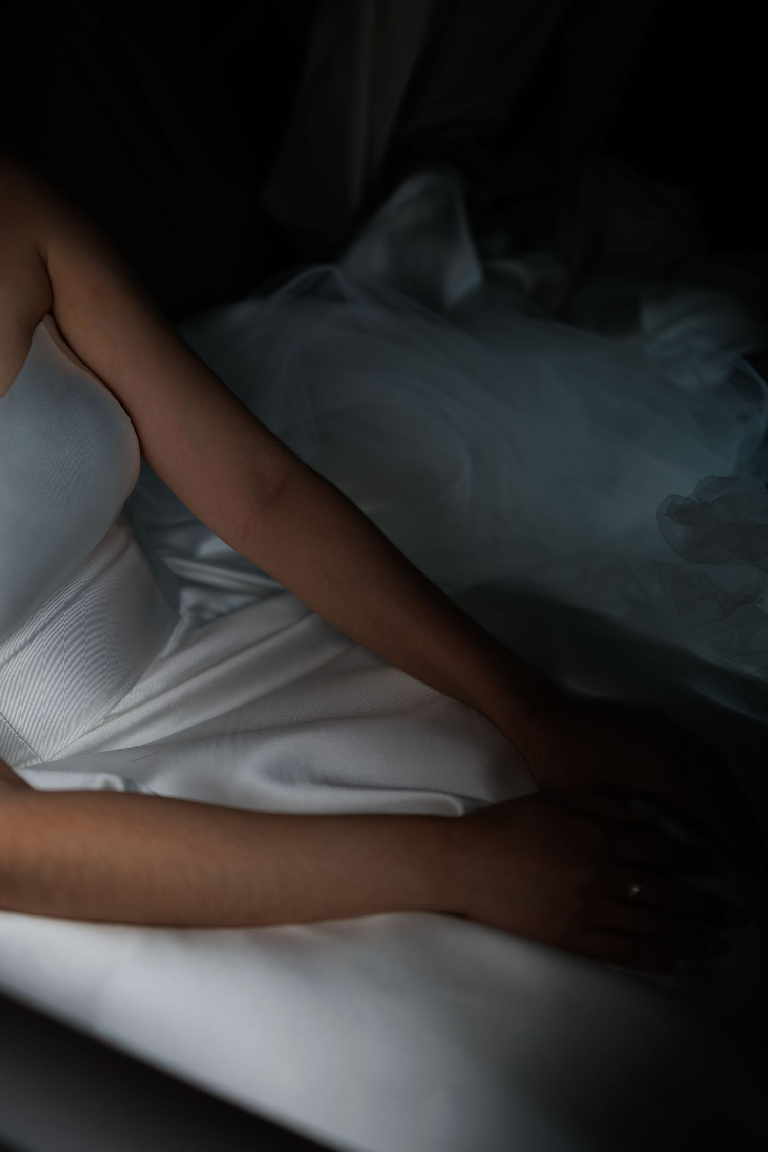 Artistic close-up of white wedding dress fabric in dramatic lighting.