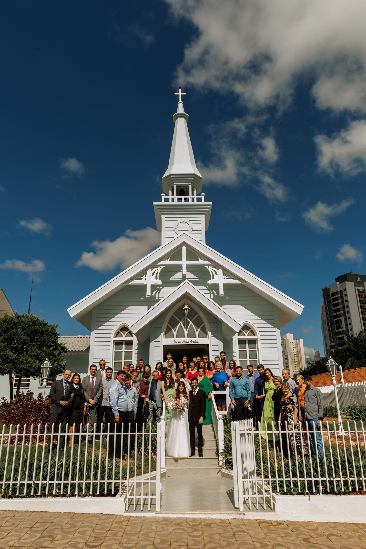 White chapel wedding venue with guests gathering outside under blue skies.