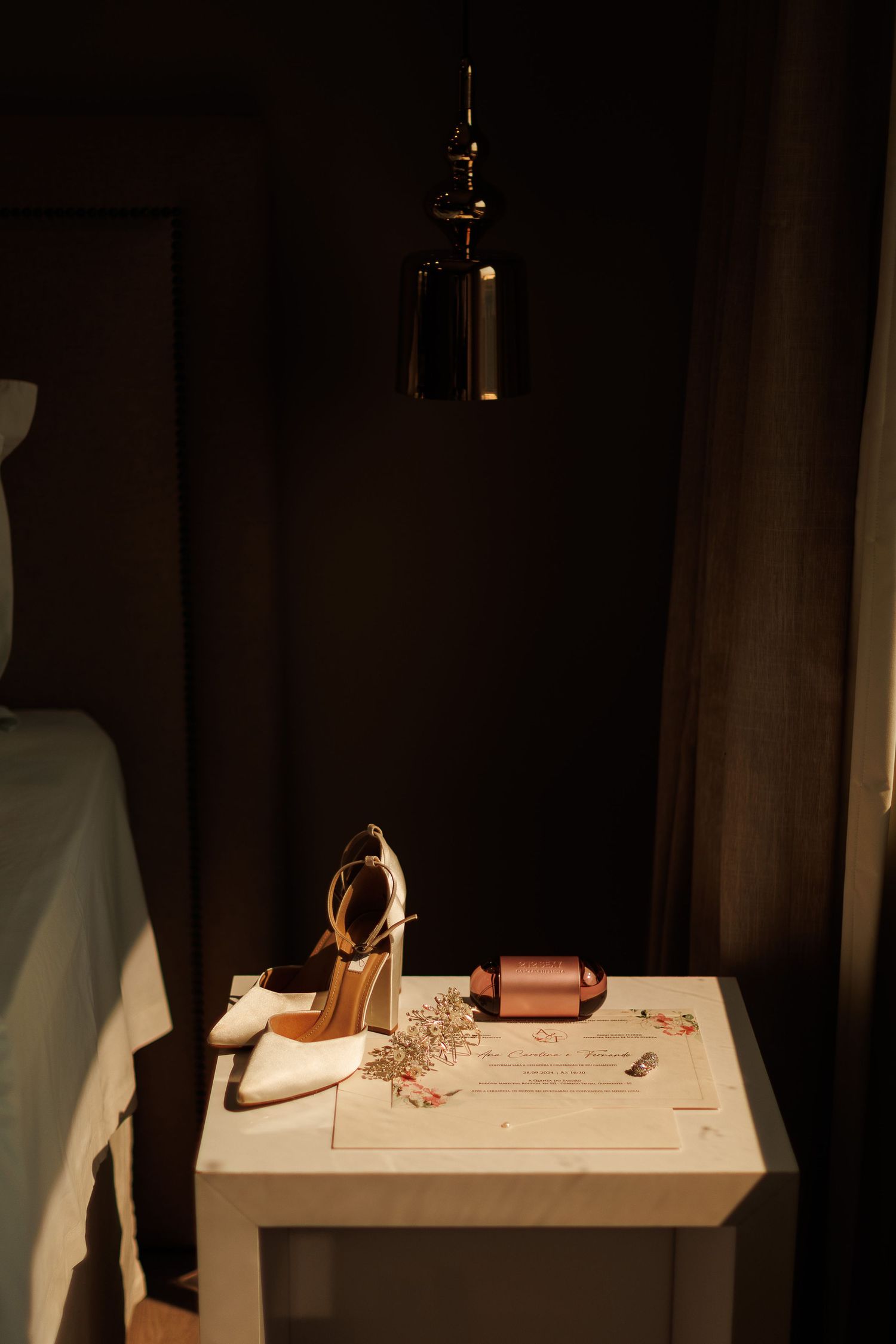 Wedding accessories and stationery arranged on table with dramatic shadows.