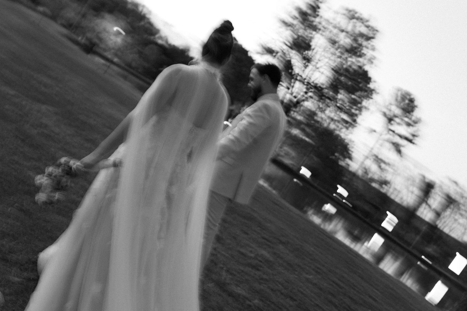 Black and white wedding photograph showing movement in an outdoor garden setting.