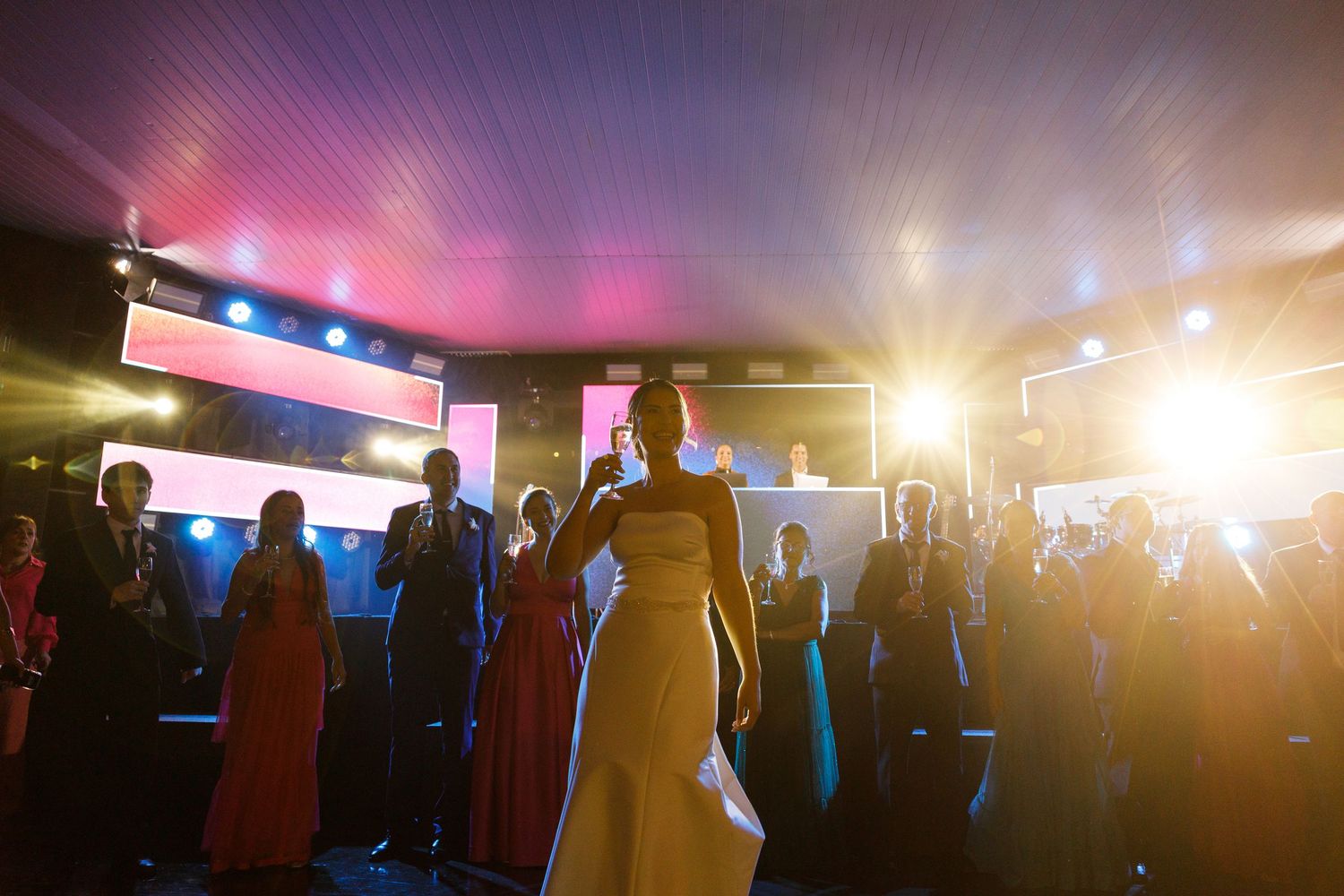 Silhouettes of people dancing at a reception with colorful lighting effects.