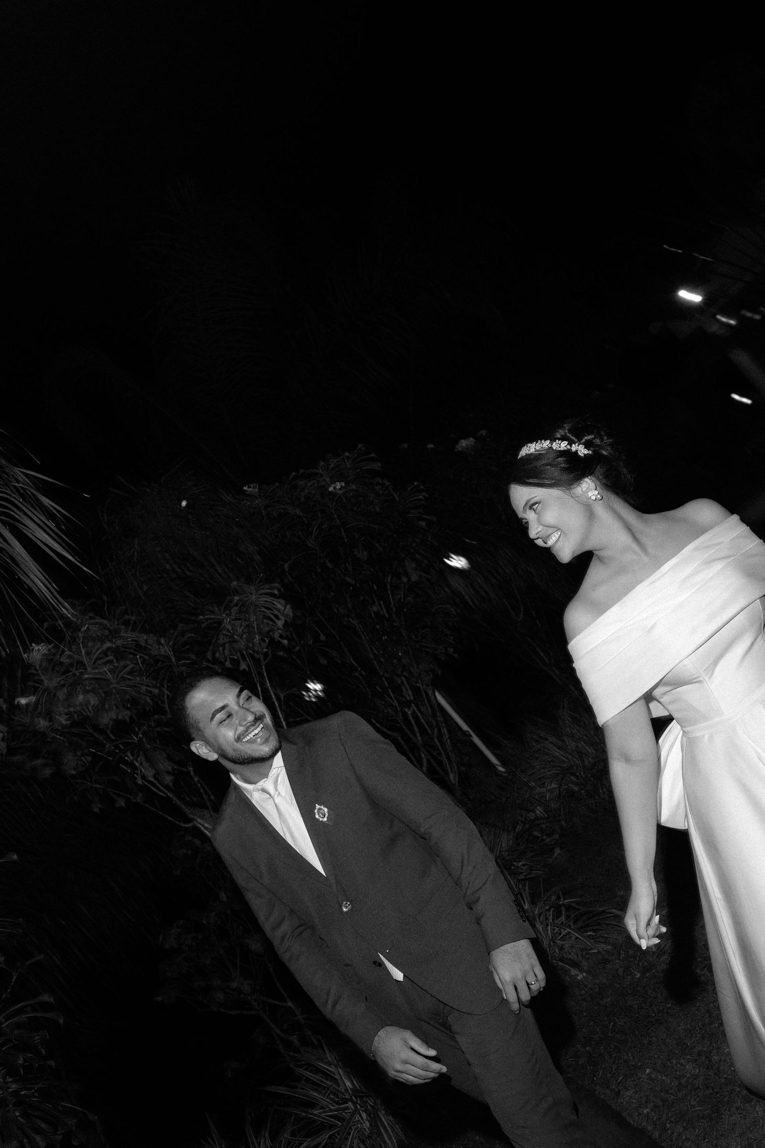Black and white candid wedding photo with dramatic shadows.