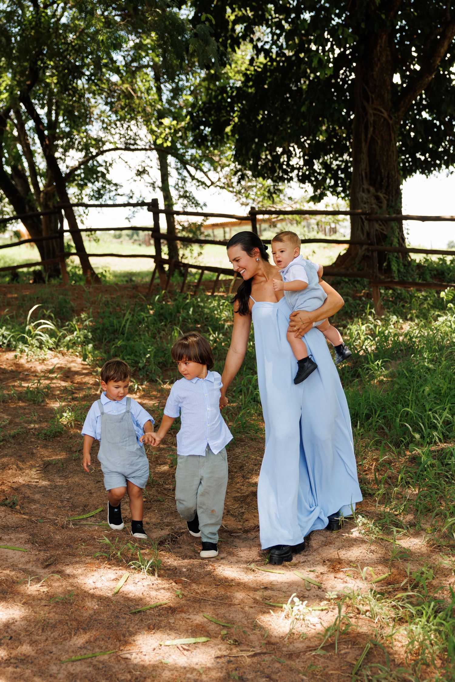 Family wearing coordinated blue and white outfits playing under trees in a park.