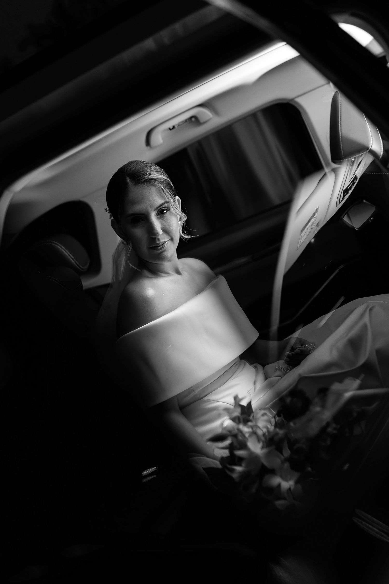 Dramatic black and white photo of a bride sitting in a car.