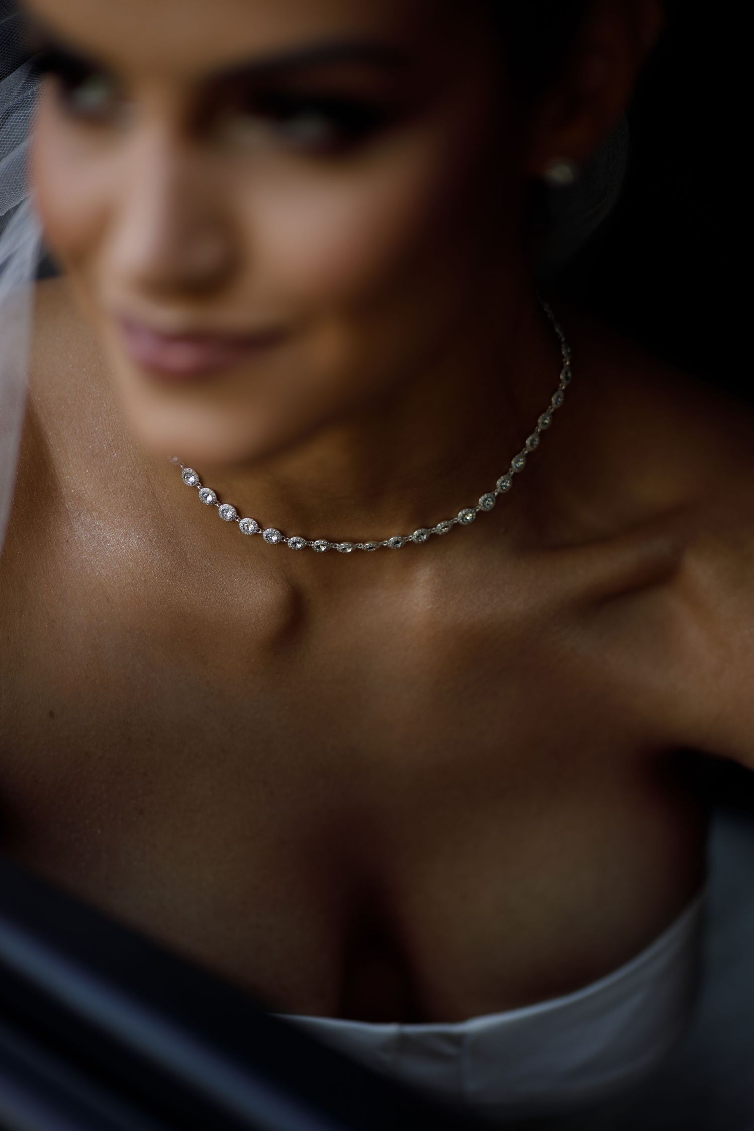 A delicate crystal necklace sparkles against soft lighting in an elegant wedding detail shot.