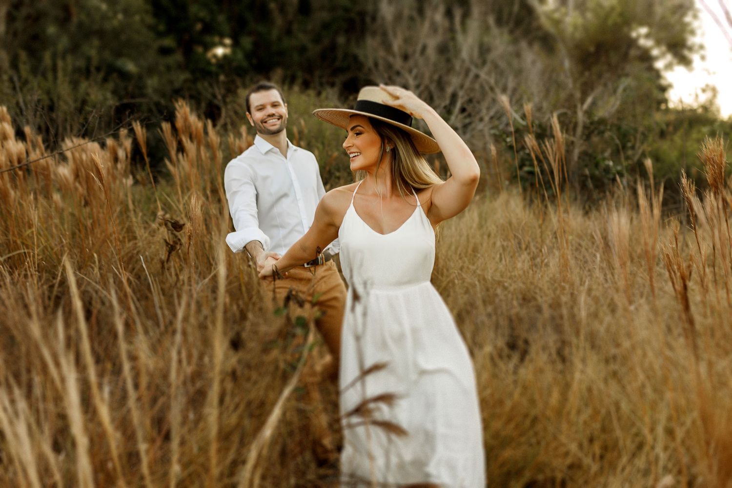 A romantic outdoor photoshoot in a field of tall grass during golden hour.