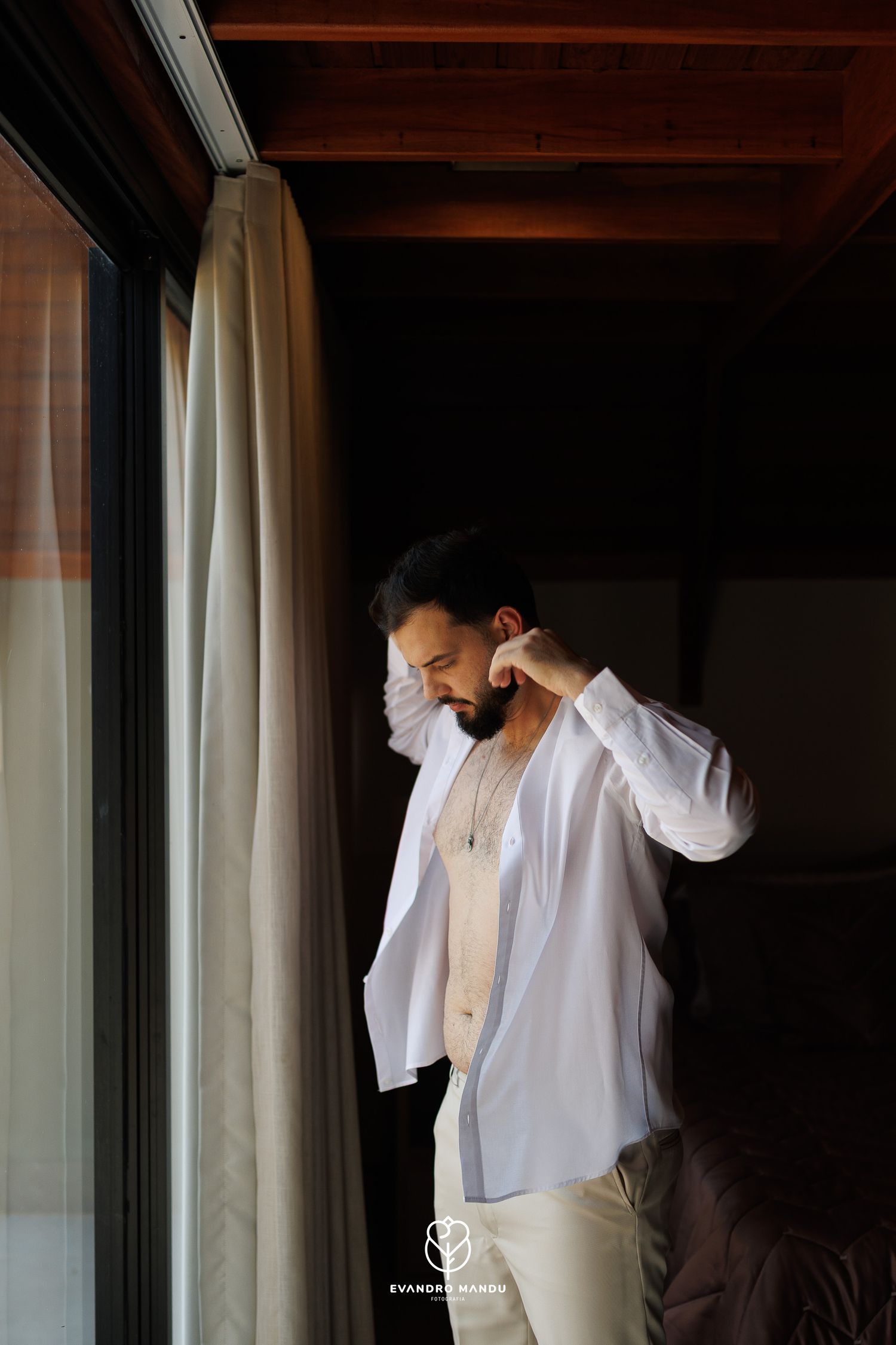Artistic sequence of getting dressed in white formal attire by a window.