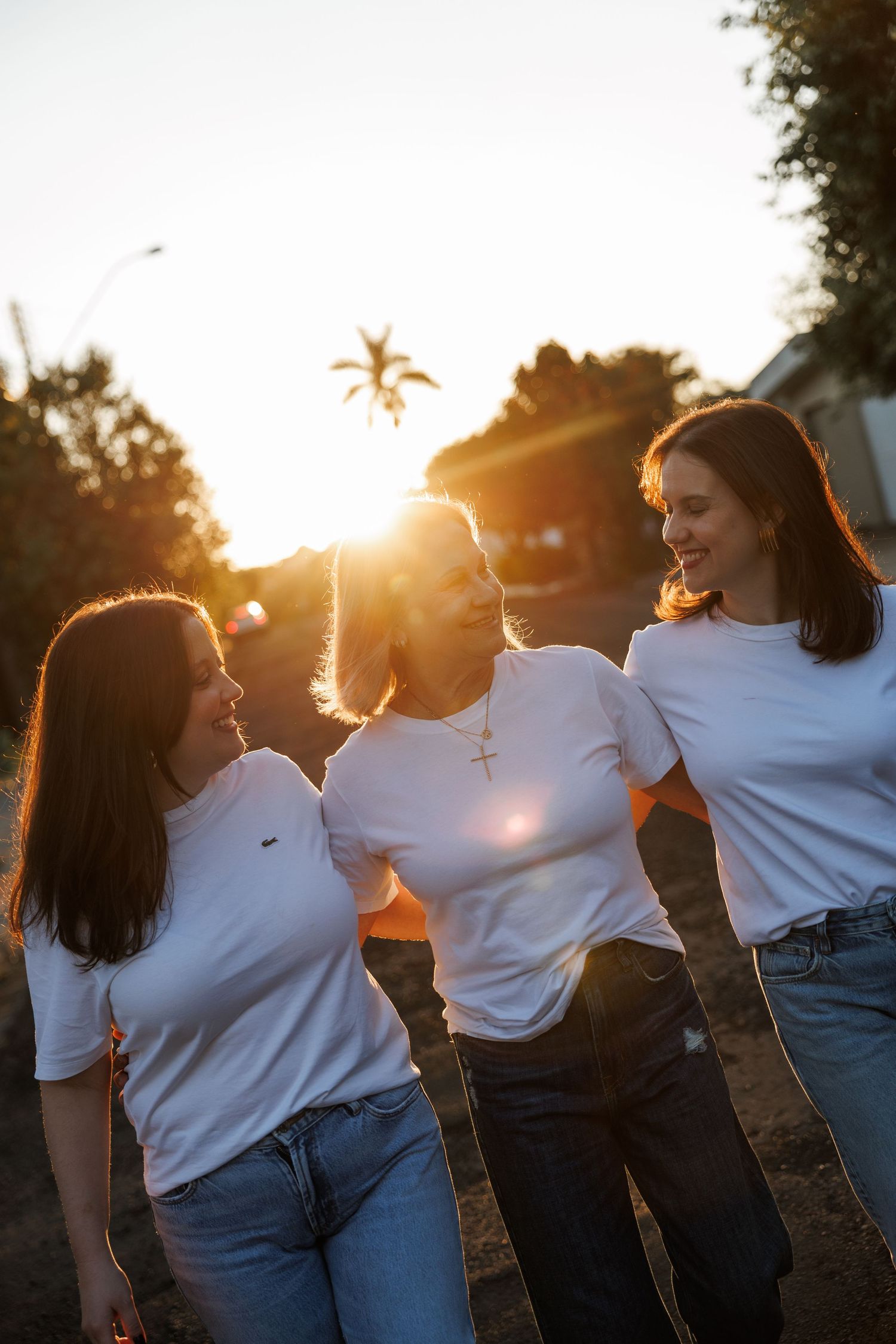Silhouettes of people in white shirts and jeans dancing together at sunset.