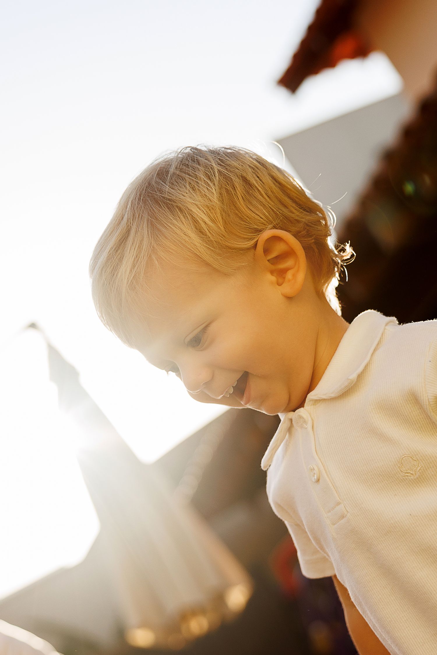 Child's profile backlit by bright sunlight creating a golden glow effect.