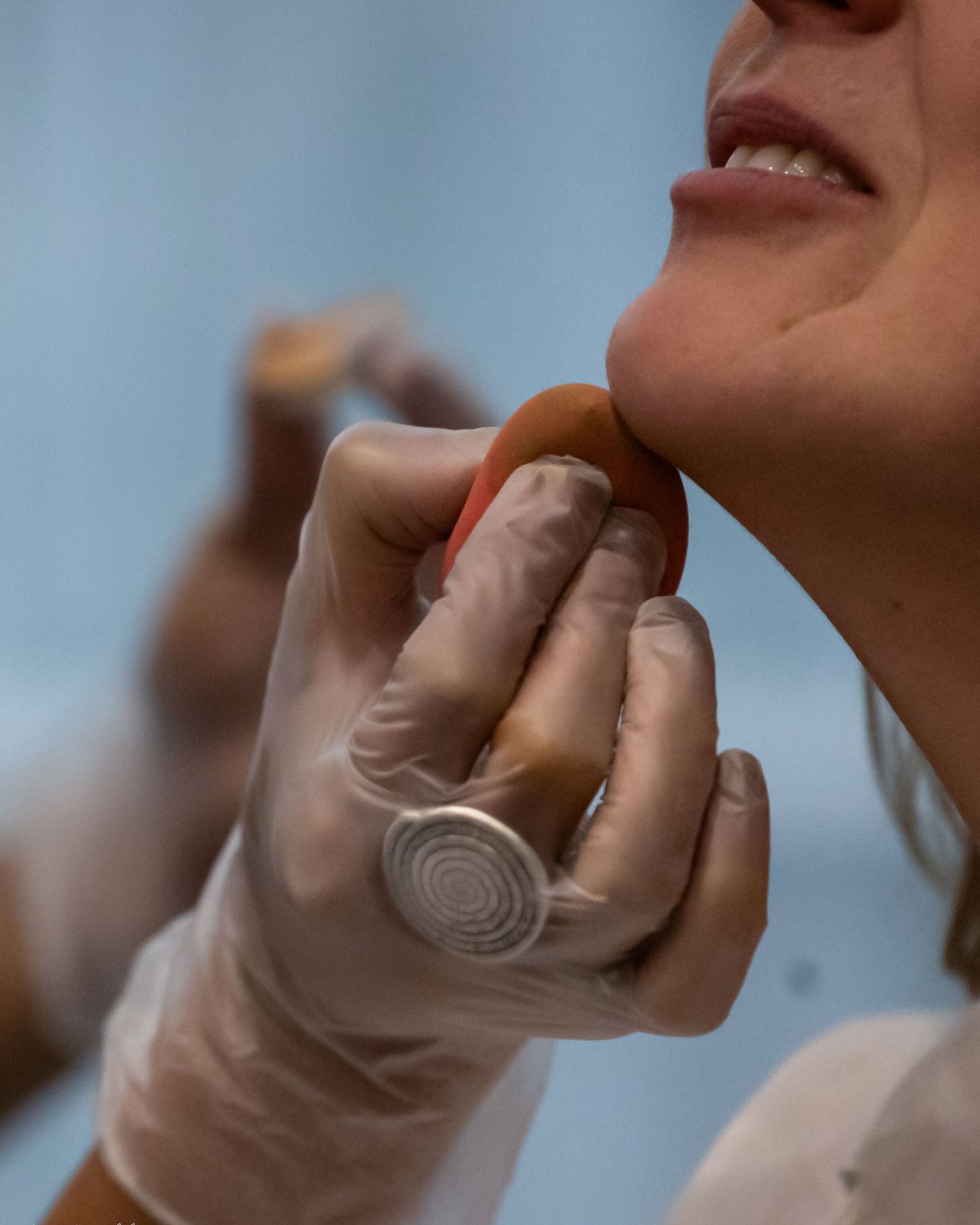 Close-up of a makeup artist at work, blending foundation along the jawline with a sponge, soft light and calm focus before the big moment. !