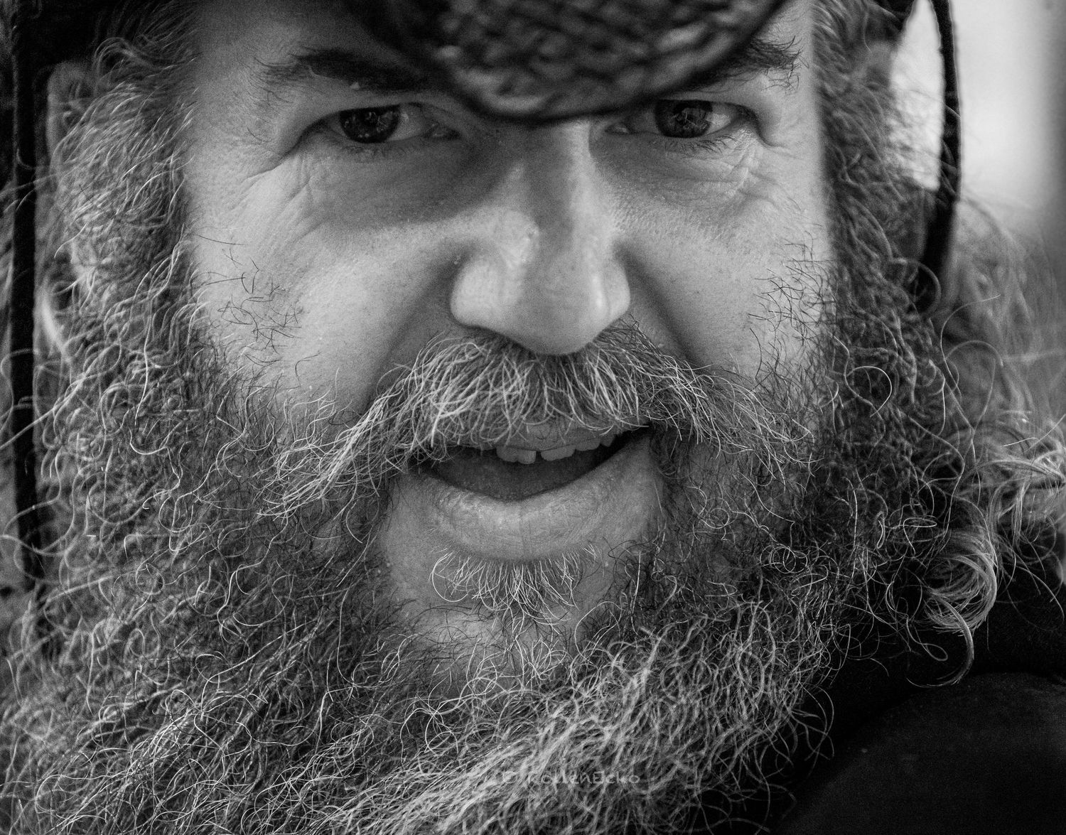 Black and white close-up of a bearded man with intense eyes and textured detail, showcasing character photography and expressive storytellin