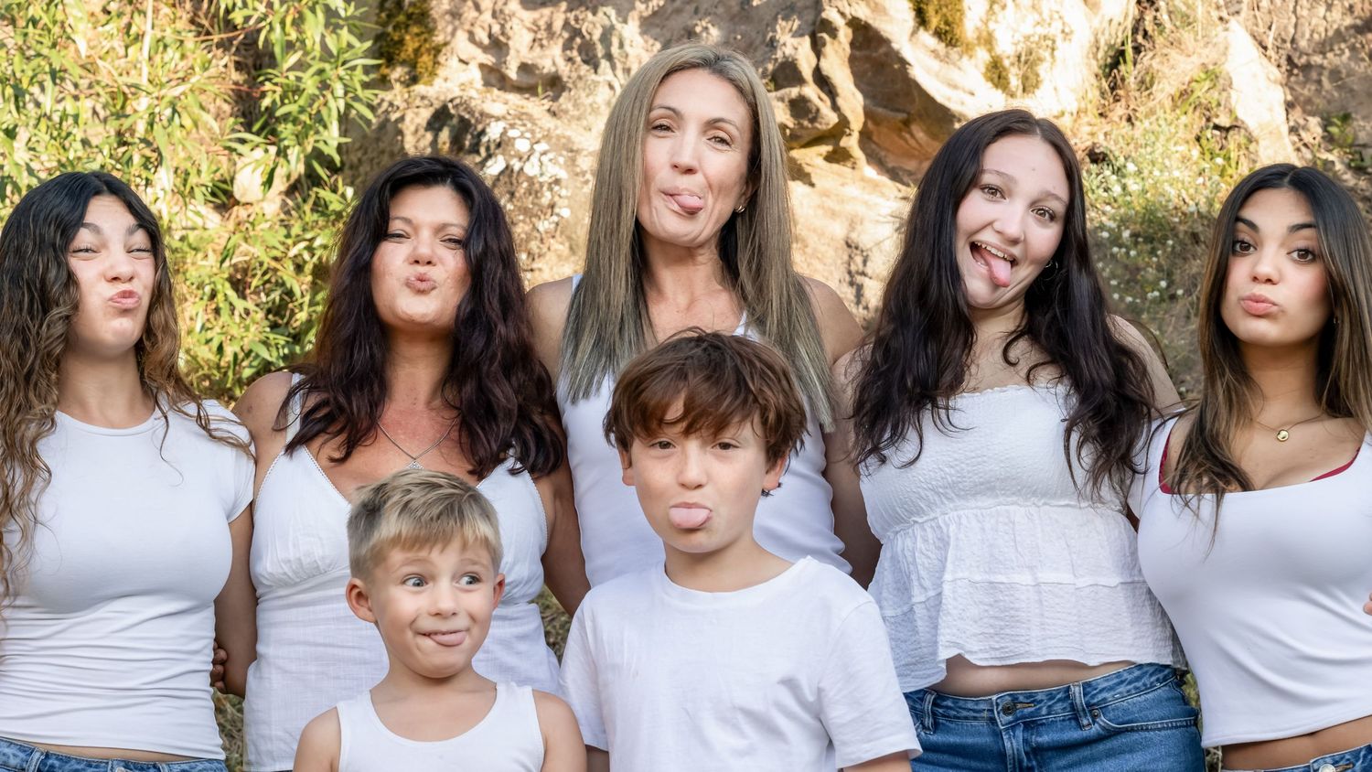 Fun outdoor Christmas family portrait with kids and parents making playful expressions, natural light lifestyle photography session.