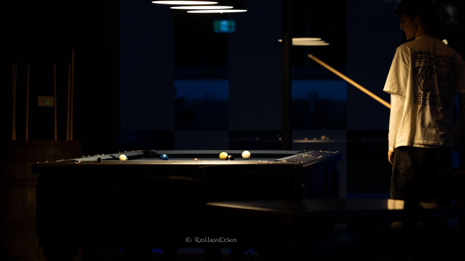 Moody low light photo of a pool player lining puma shot indoors, cinematic shadows and dramatic lighting showcasing creative lifestyle photo