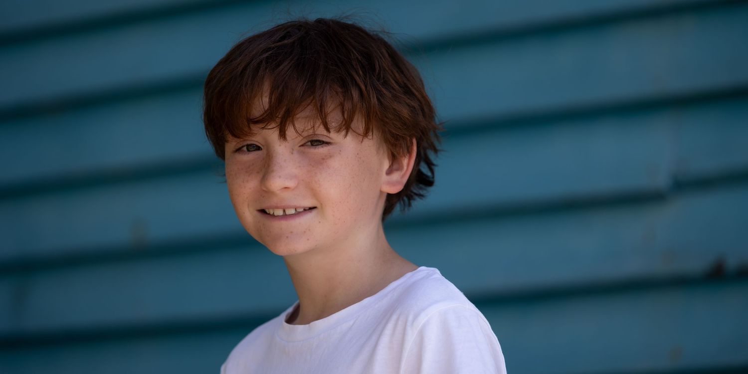Outdoor portrait of smiling freckled boy in soft light, perfect for Christmas family photos and holiday portrait sessions.