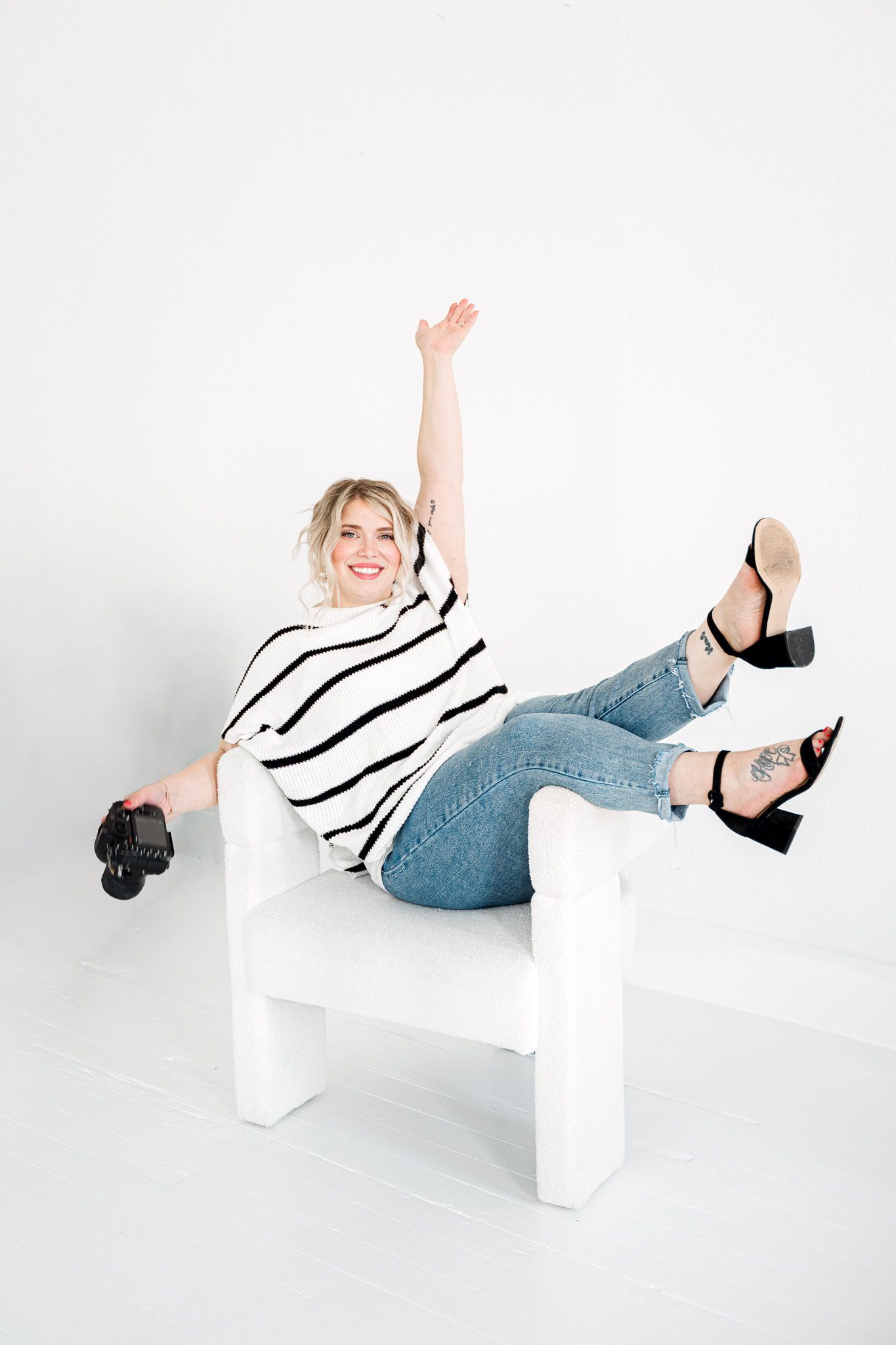 Ryan Jordanstriped top and jeans posing playfully on white blocks against white background in studio setting.  Wedding Photographer tyler tx