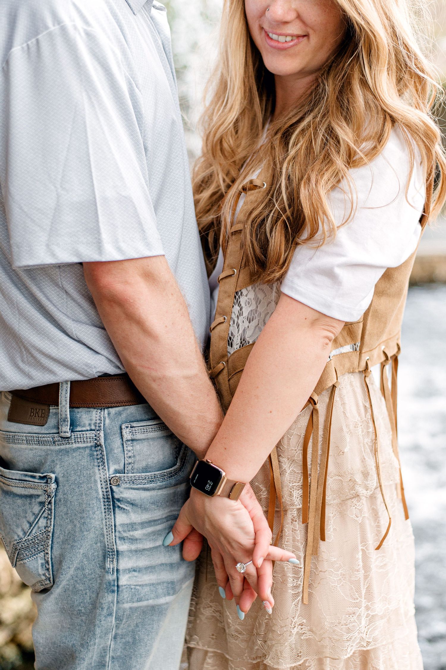 A couple in casual denim and beige clothing embracing in a romantic pose against a light background.