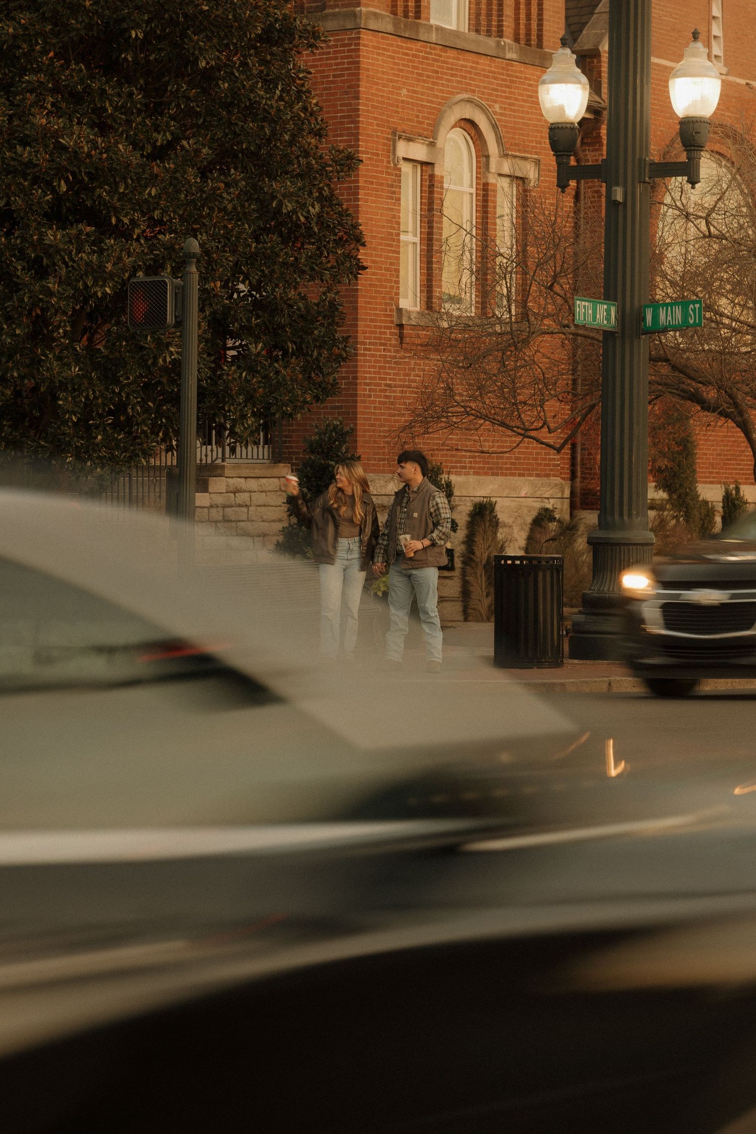 Urban street scene with brick buildings and lamp posts at dusk.