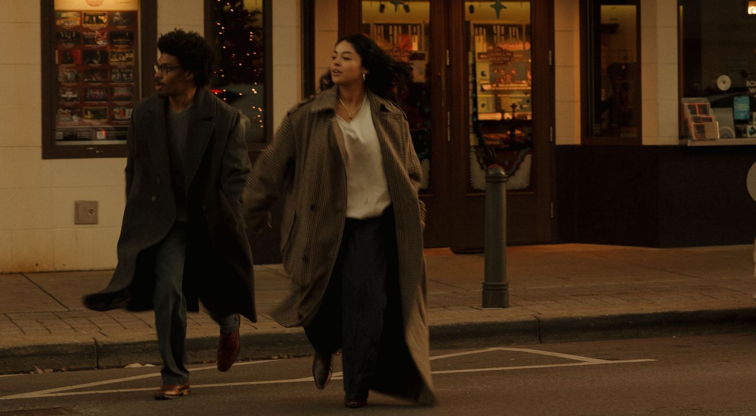 People walking past storefronts at dusk in urban setting.