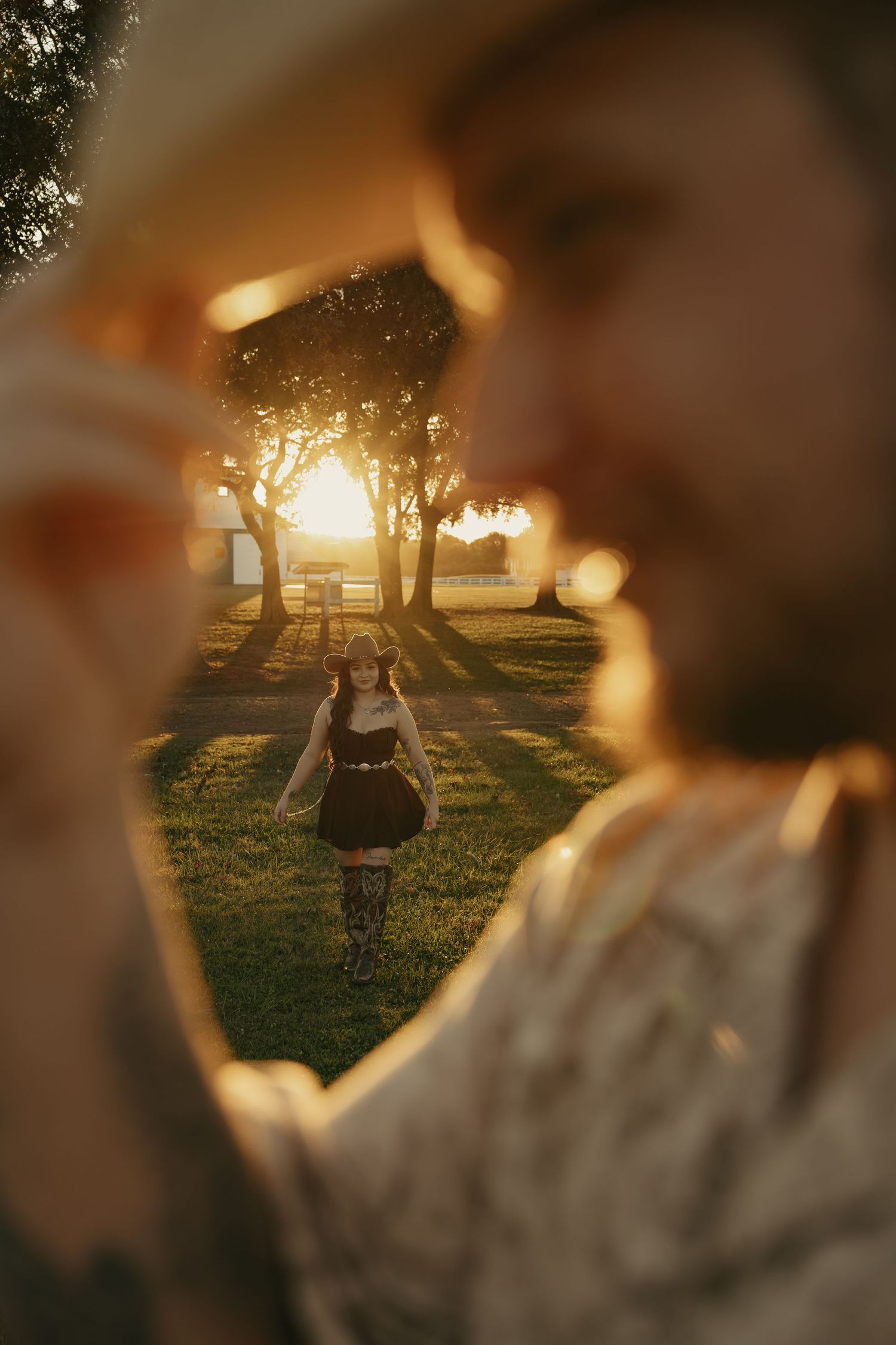 A dreamy sunset scene with a person in a dress twirling in a golden-lit meadow with trees silhouetted against the sky.