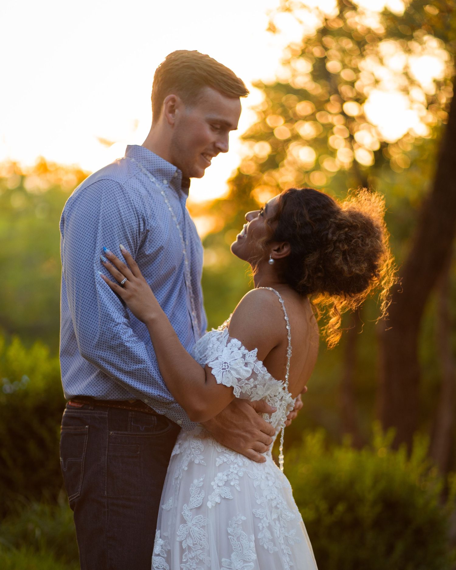 Romantic couple embraces during sunset wedding photoshoot in outdoor setting.