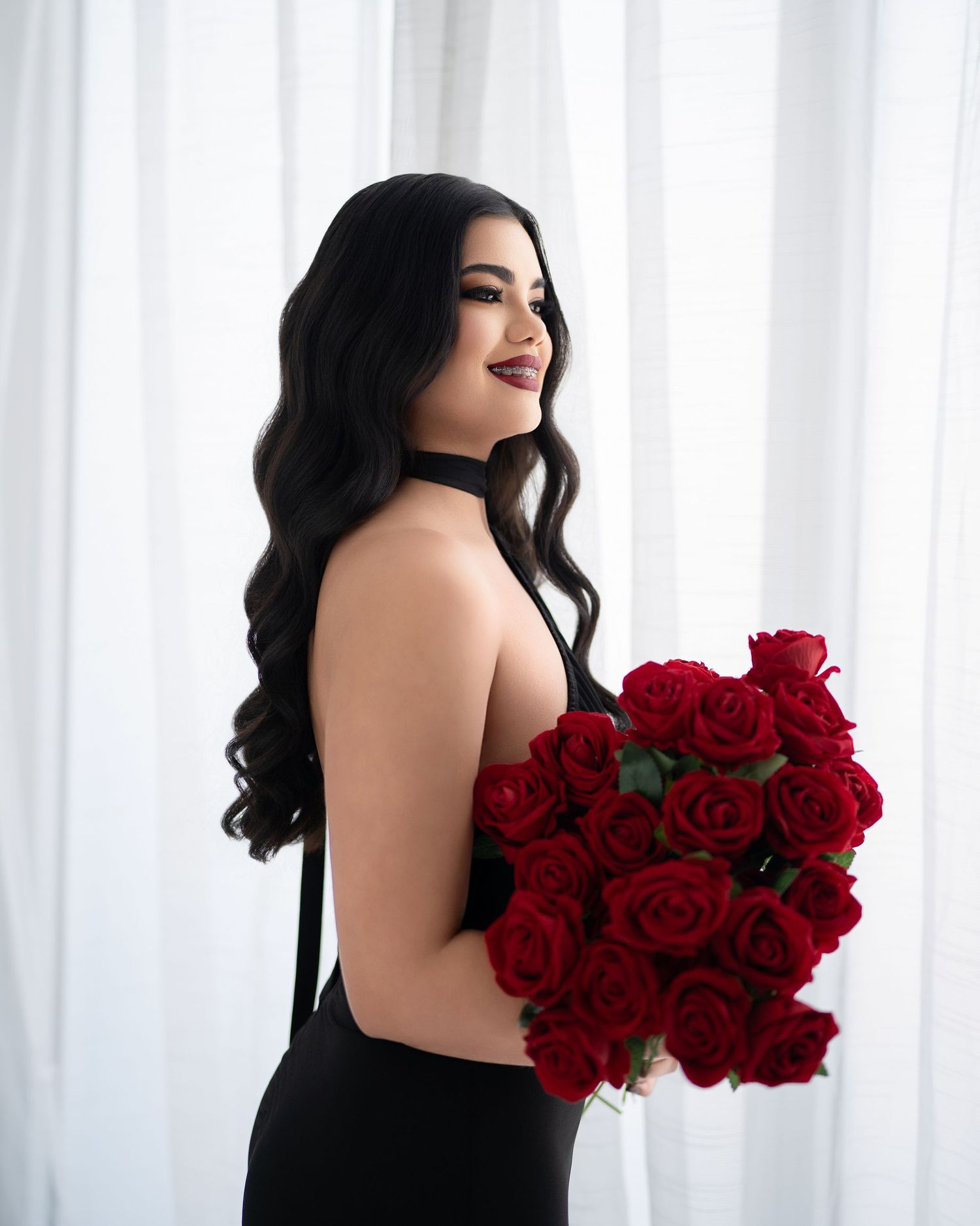 Glamour portraits featuring black evening gown and bouquet of red roses.