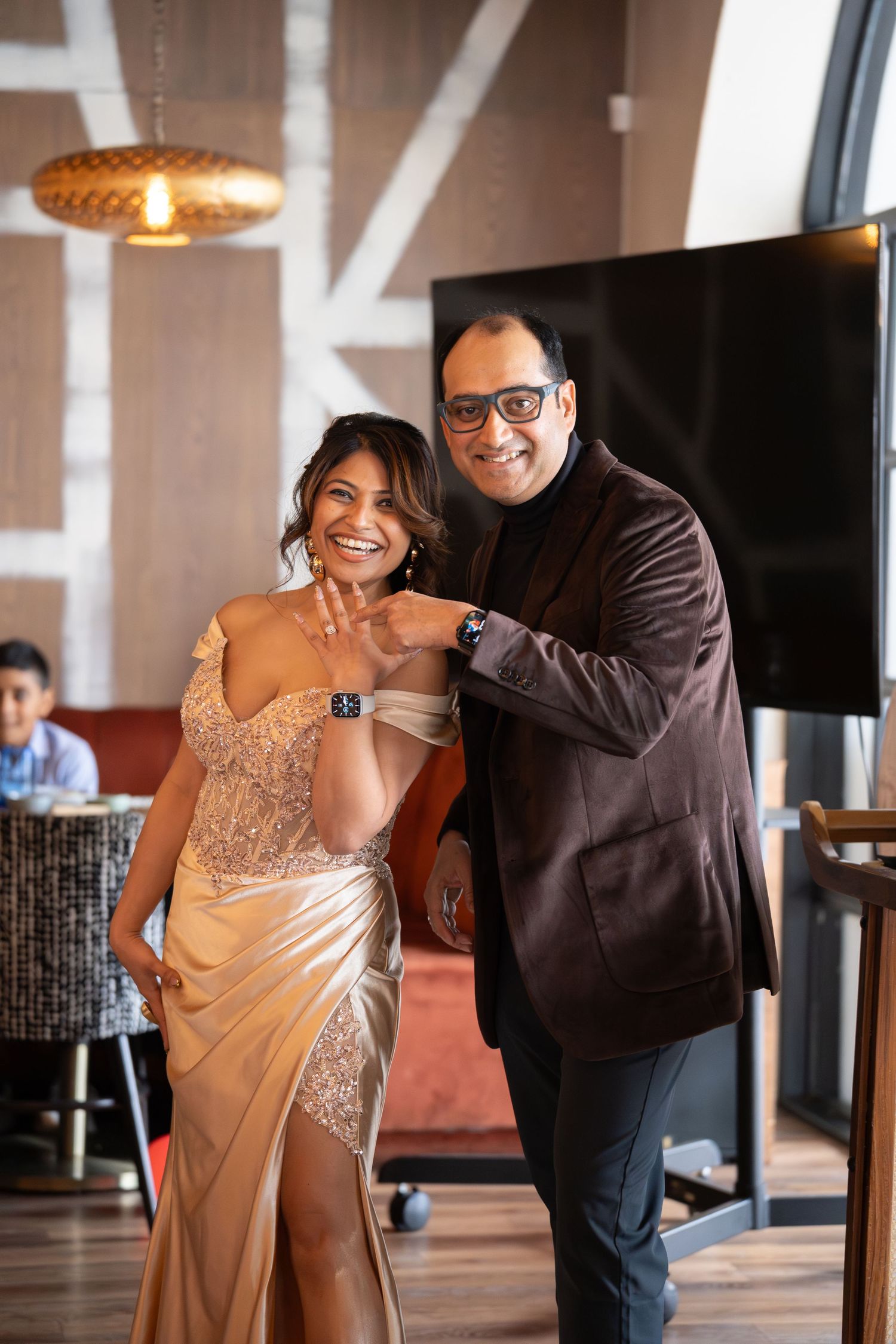 Couple poses together at indoor venue wearing formal evening attire.