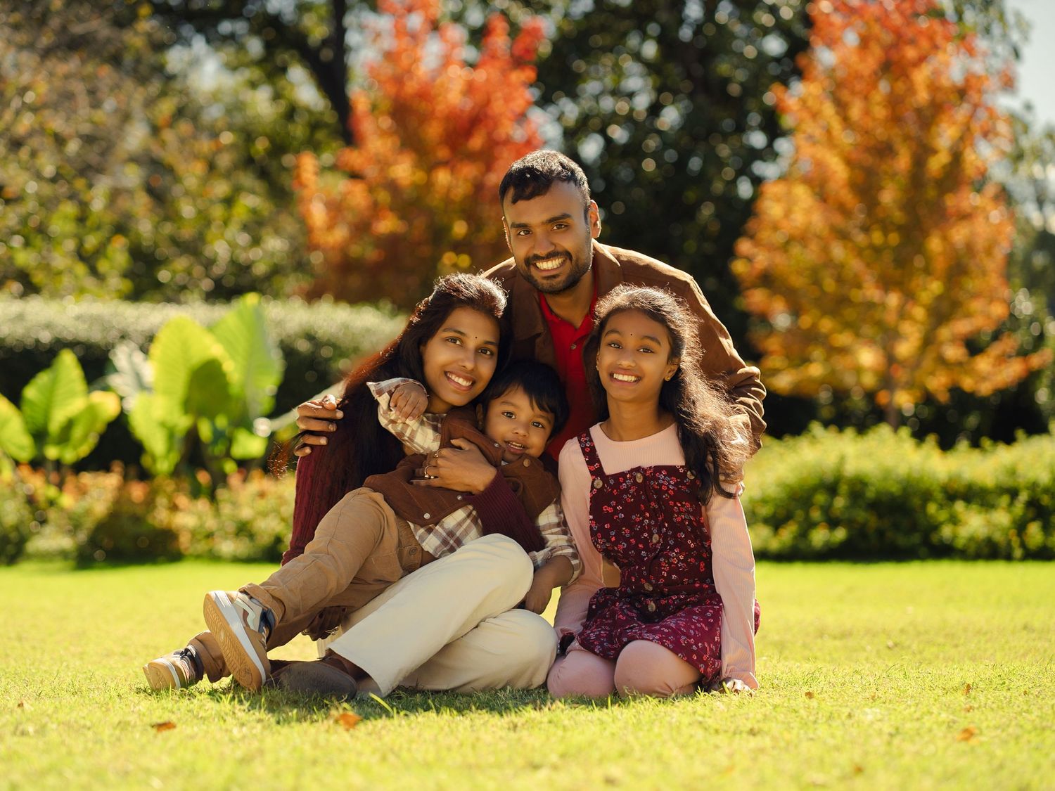 Family enjoying a sunny autumn day while relaxing on grass in a park.