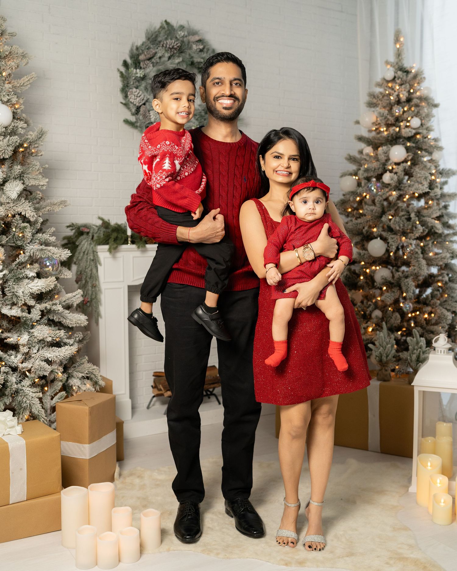 Holiday family photos with Christmas trees and wrapped presents in studio setting.