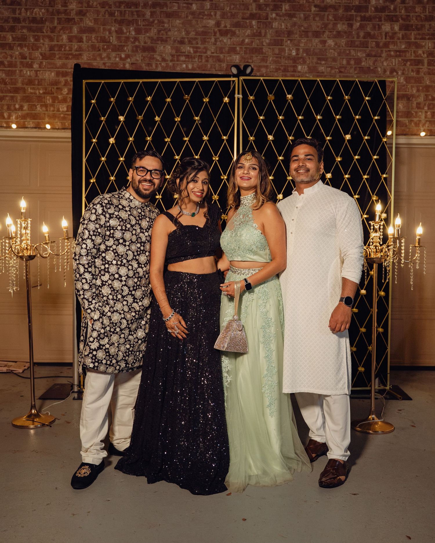 A group poses together at an elegant indoor venue with chandelier lighting and decorative lattice backdrop.