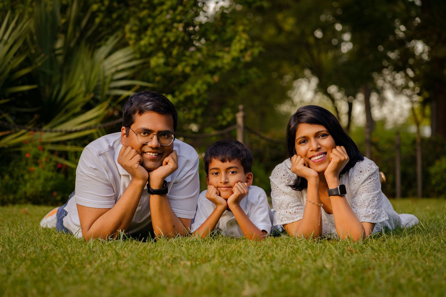 Family laying on grass together during outdoor photo session.