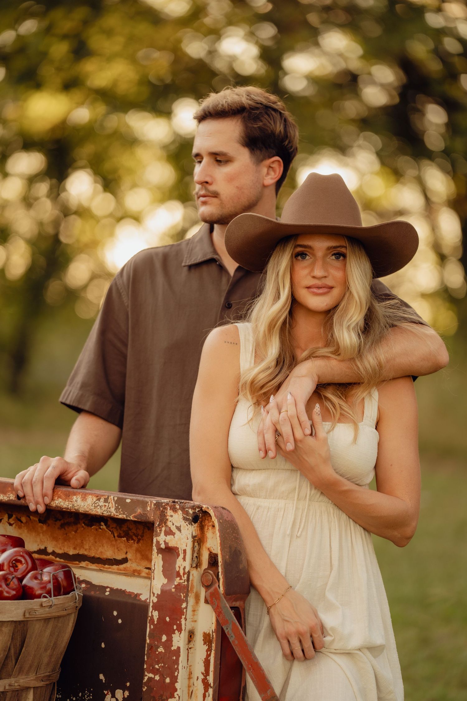 Rustic engagement photos with couple posing against vintage wooden crate in warm sunlight.