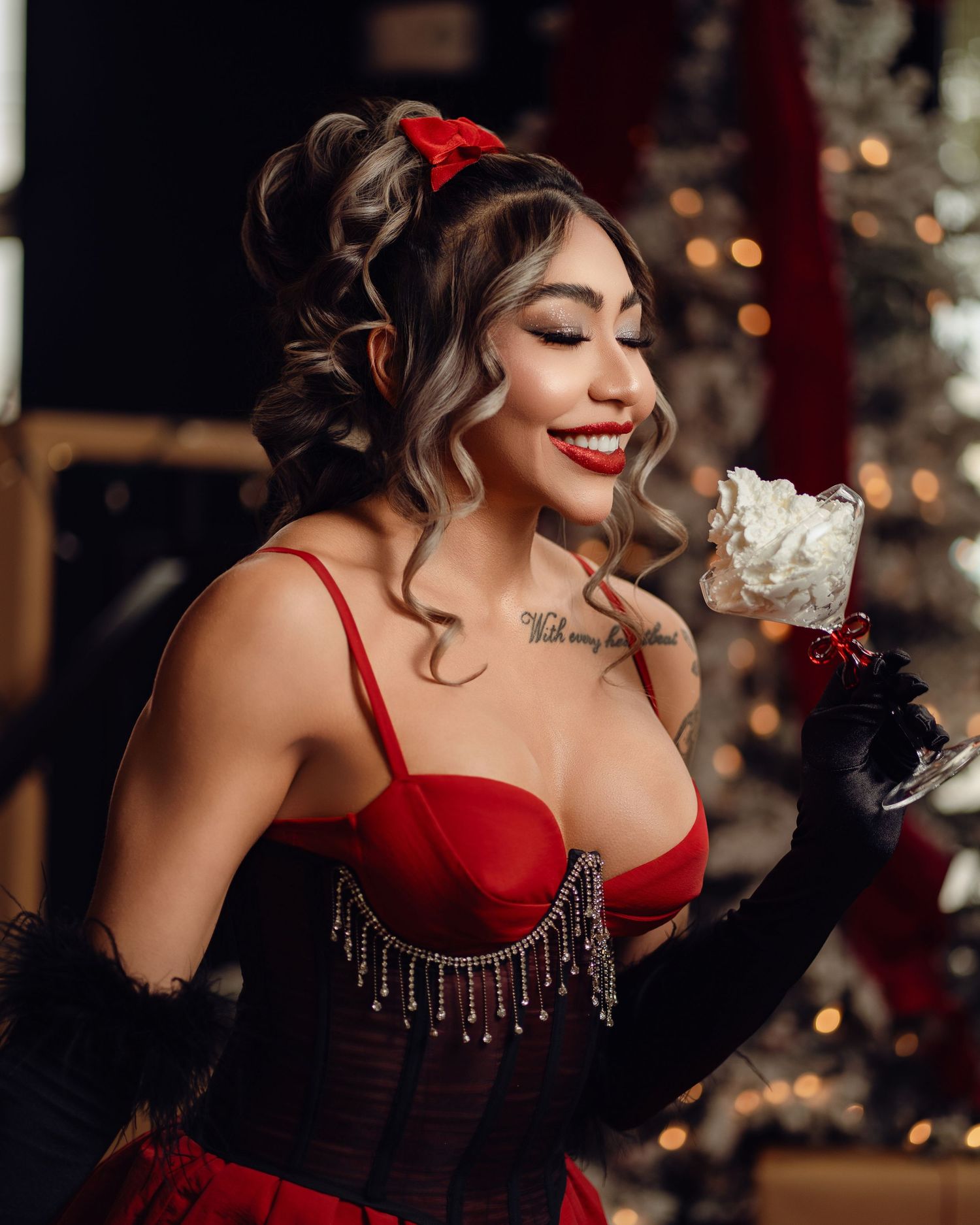 Woman in red corset gown with black gloves holds a cocktail, smiling at holiday party.
