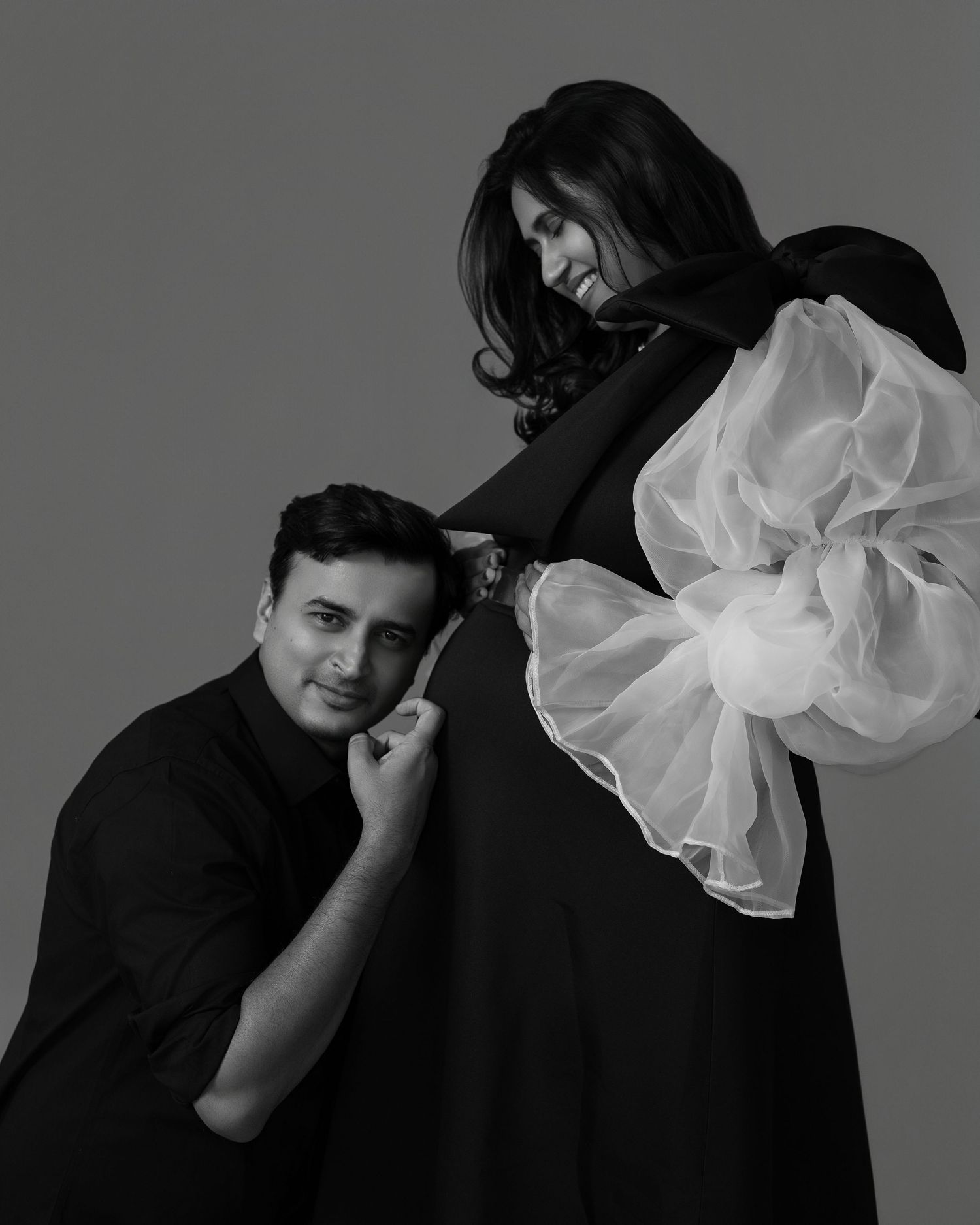 Dramatic black and white studio portraits with flowing white fabric against grey background.