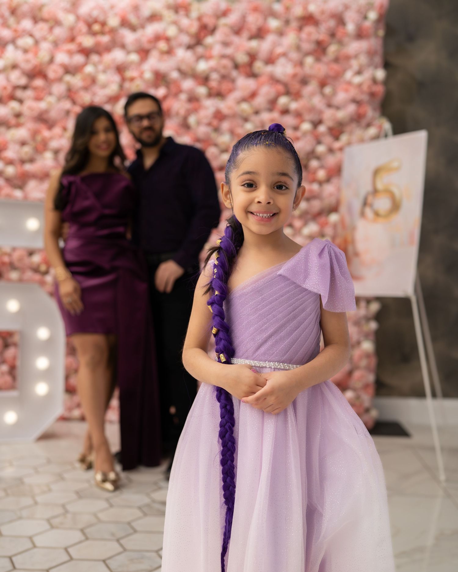 A series of photos showing someone in a lavender dress with purple accessories against a pink floral backdrop.