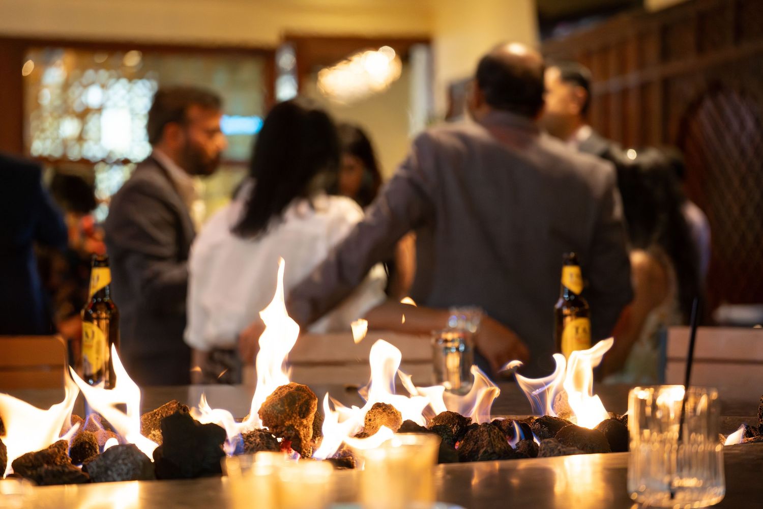 A row of fire features illuminates a modern restaurant bar area creating an elegant ambiance.