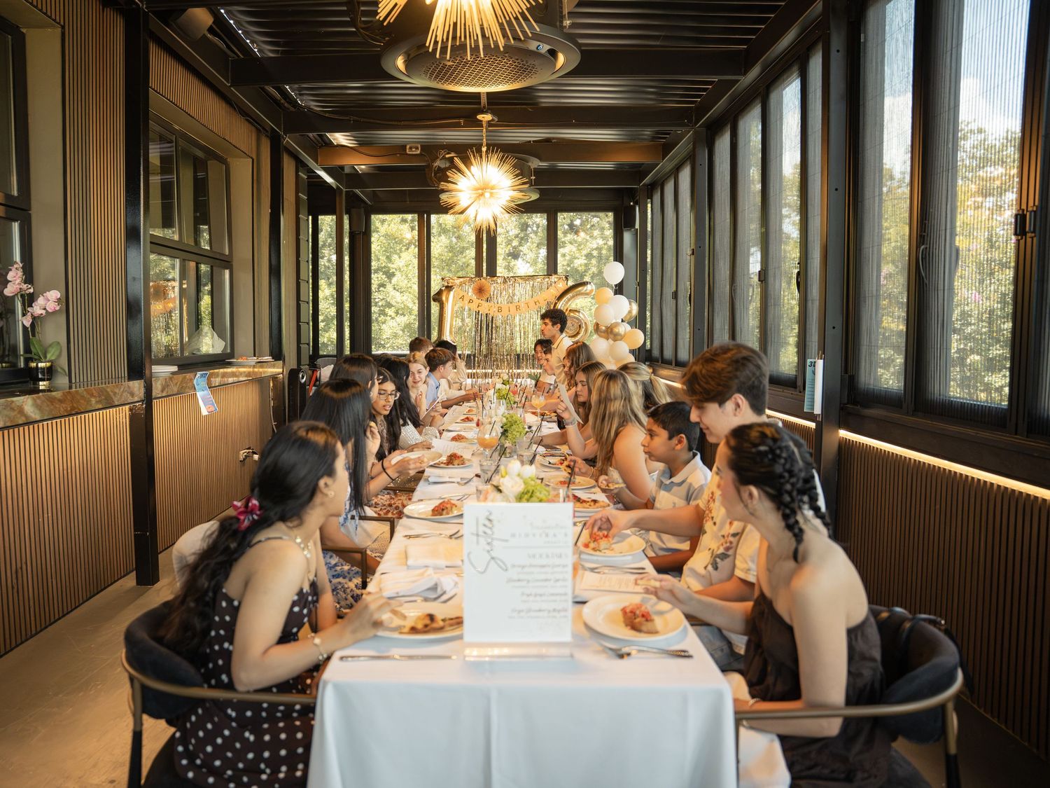 Group of women dining together in an elegant private restaurant room with large windows and warm lighting.