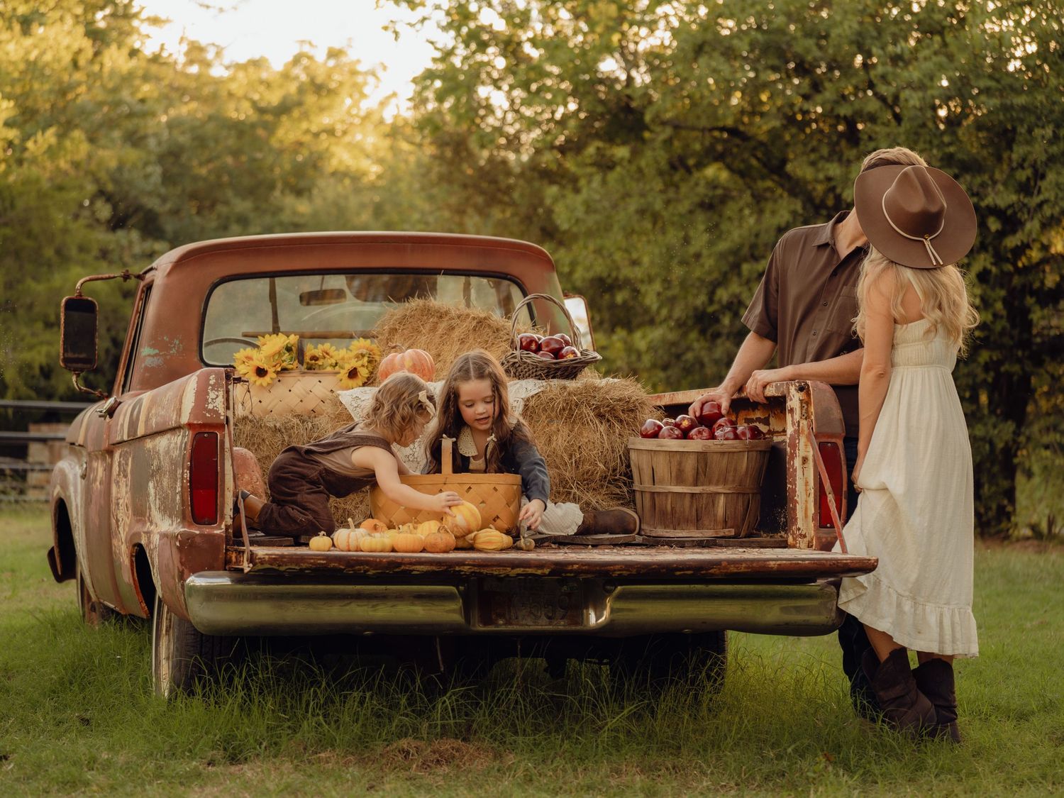 A rustic outdoor picnic setup with vintage furniture and baskets arranged on grass in warm sunlight.