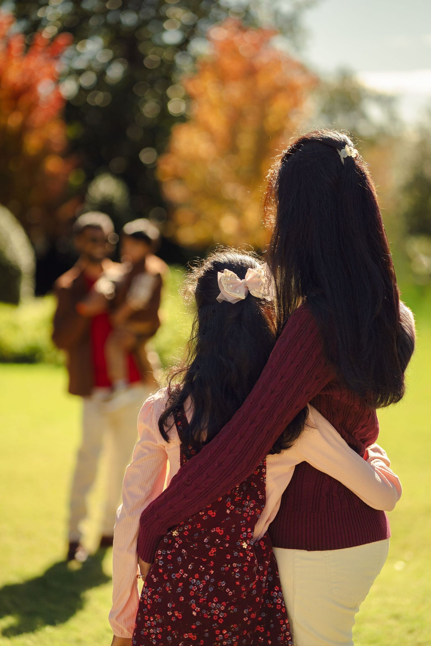Family members in coordinated burgundy and white outfits walking together in an autumn park.