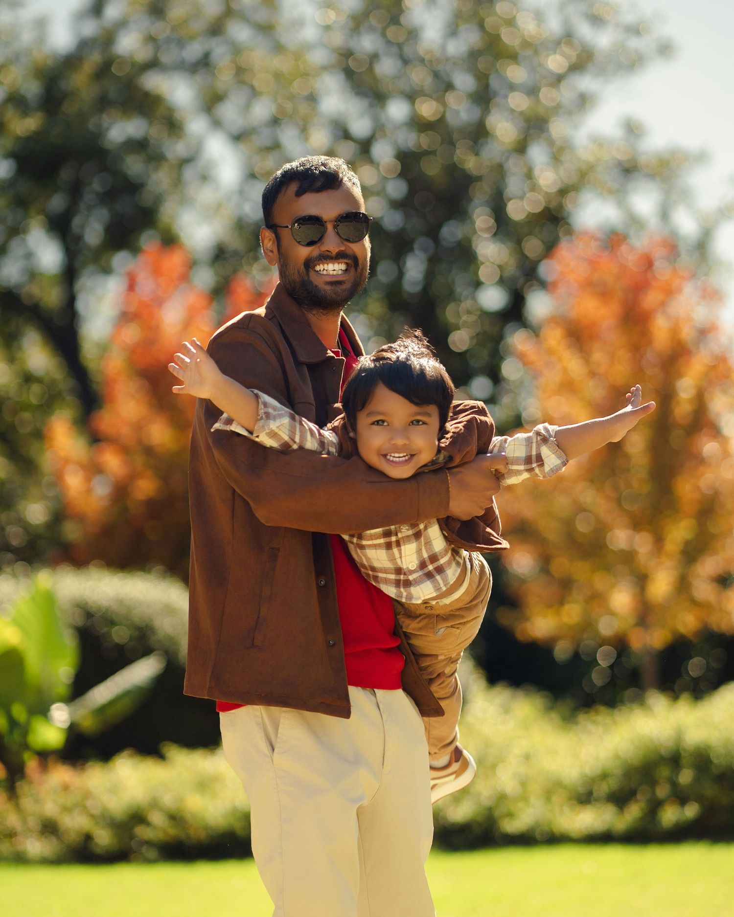 Playful family moment captured in a sun-drenched autumn garden setting.