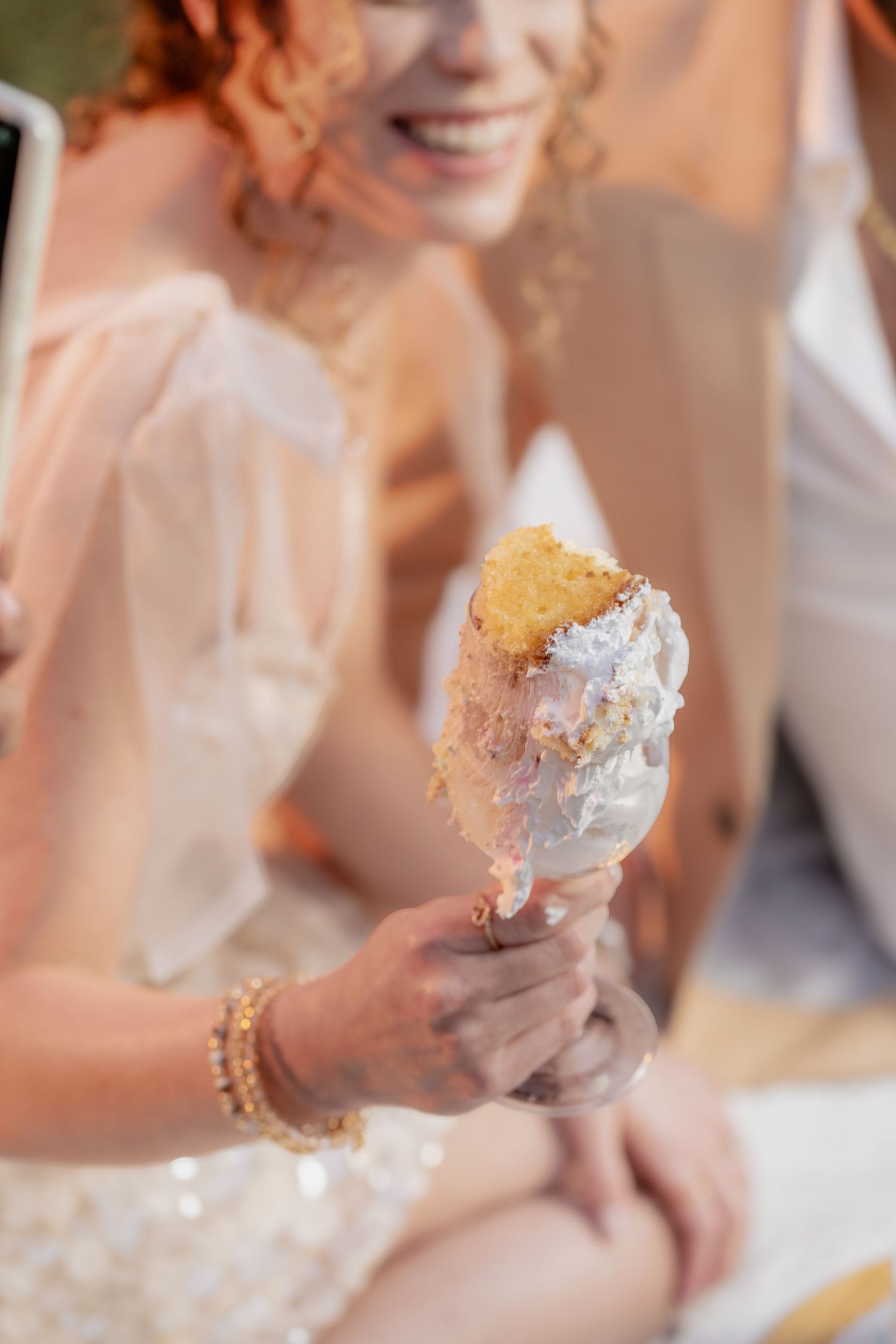 Close-up of someone holding a partially eaten ice cream cone while wearing formal attire and jewelry.