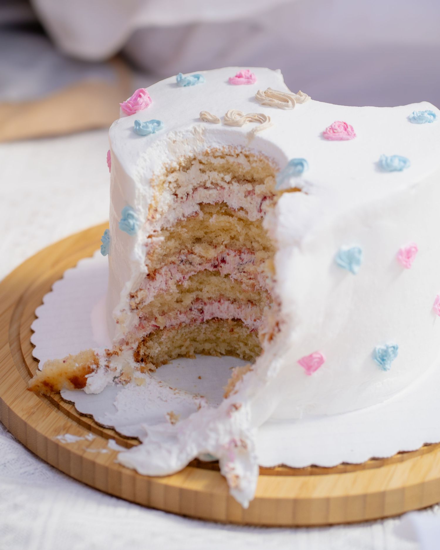 Close-up views of sliced white cake layers with pink filling displayed on a wooden serving board.