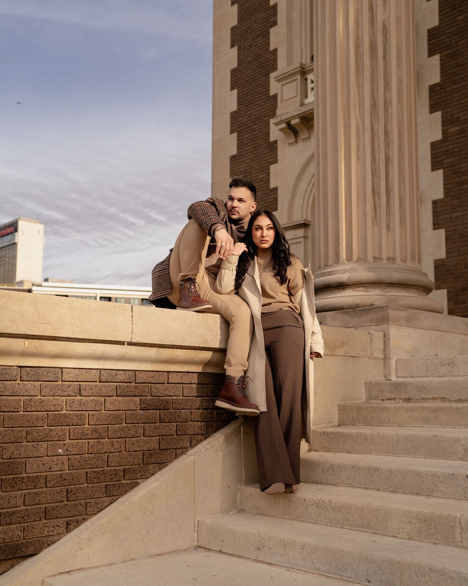 A couple poses on architectural stone steps during a romantic photoshoot at sunset.