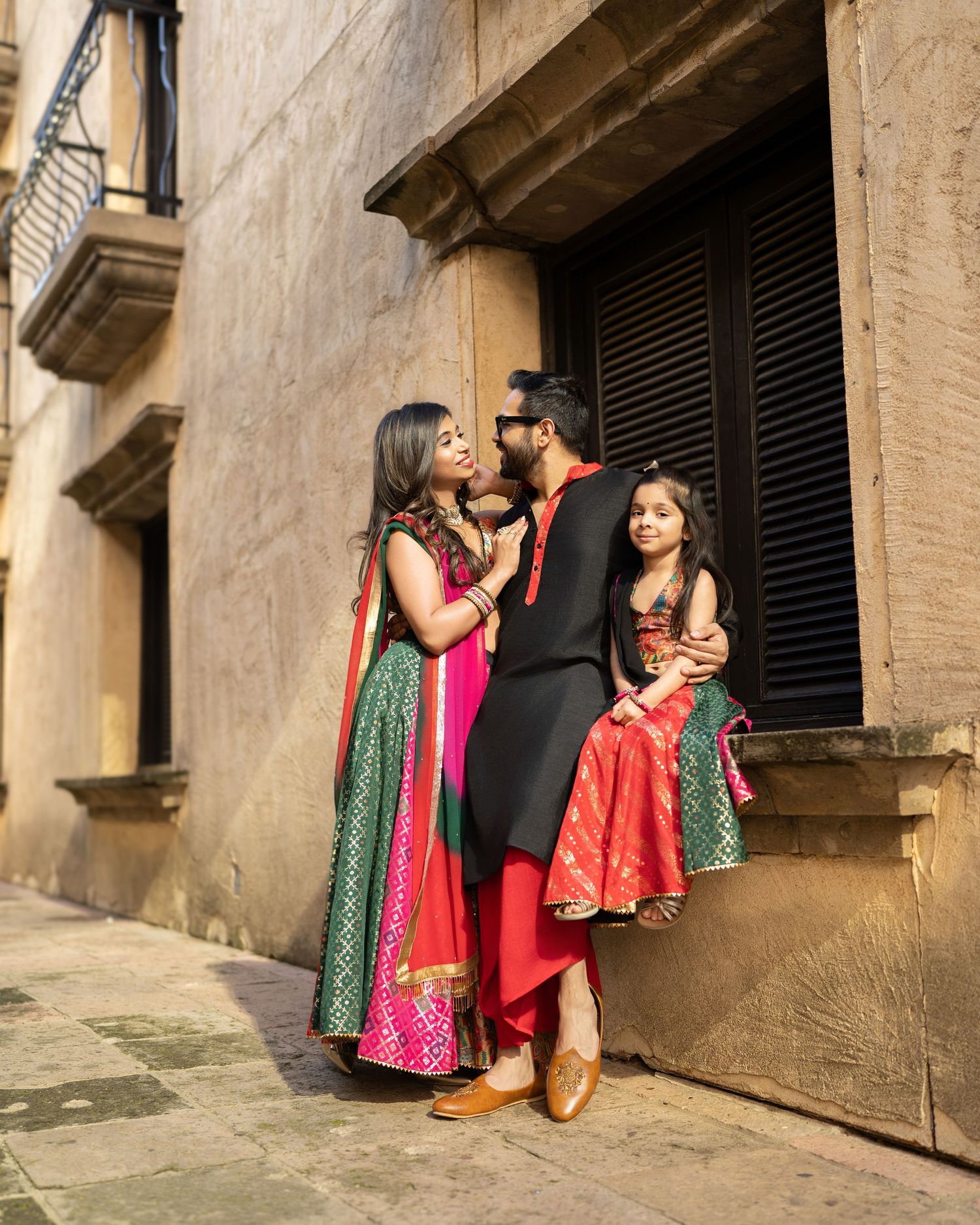 Group in traditional Indian attire posing against stone wall.