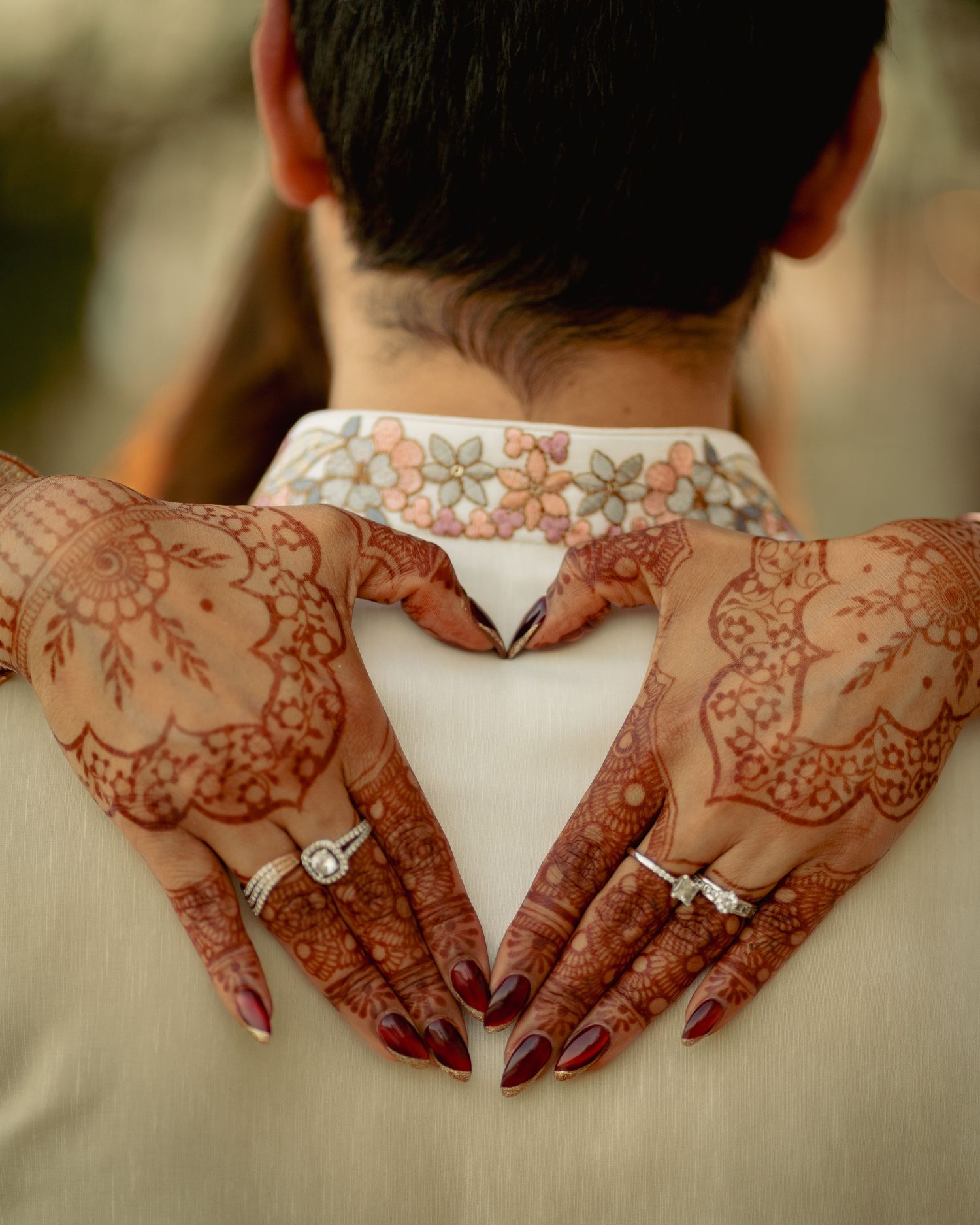 Detailed view of intricate henna designs on hands displaying an engagement ring.